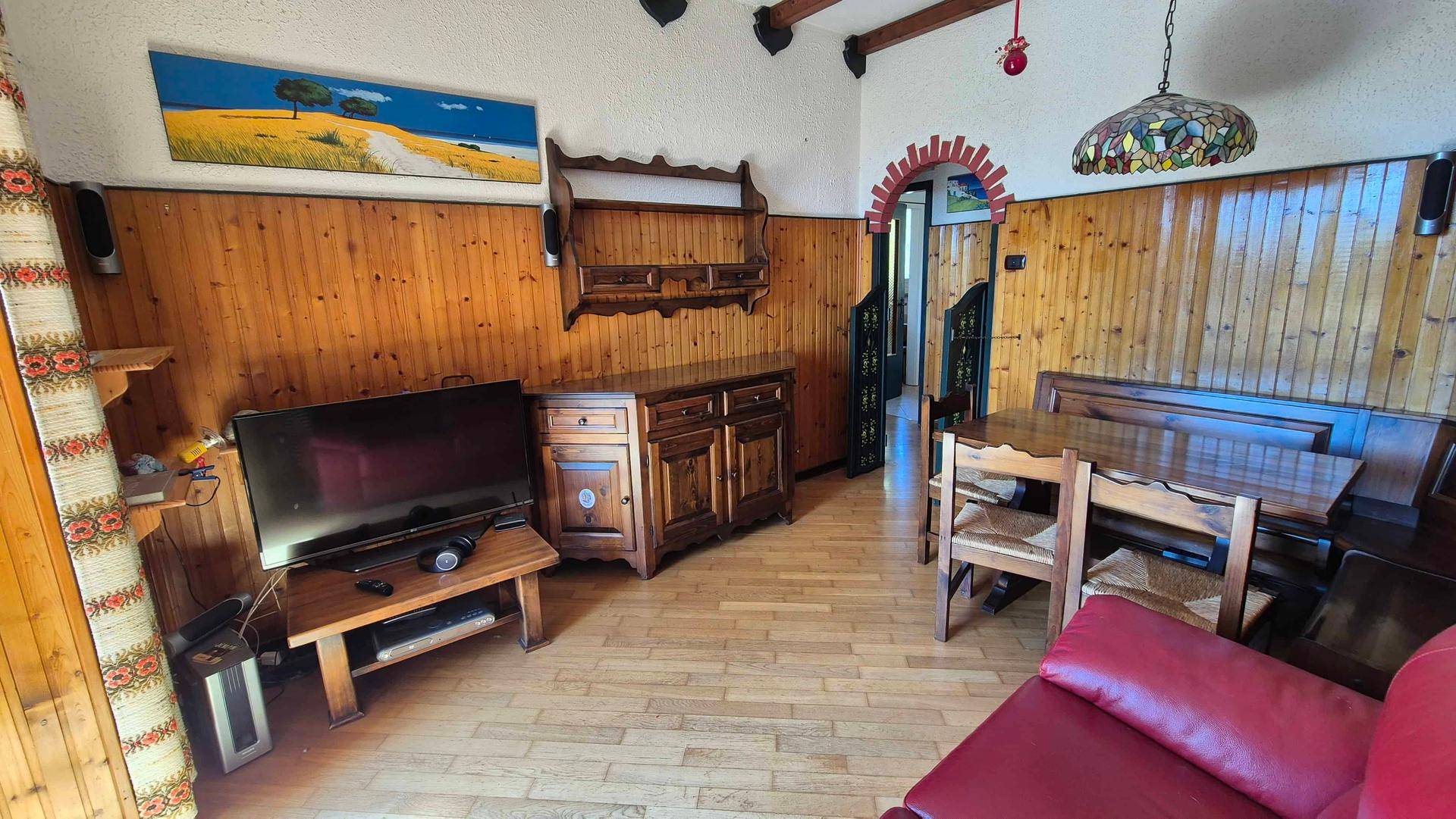 Rustikaler Wohn- und Essbereich mit Holzvertäfelung, Holzbalken und traditionellen Holzmöbeln.