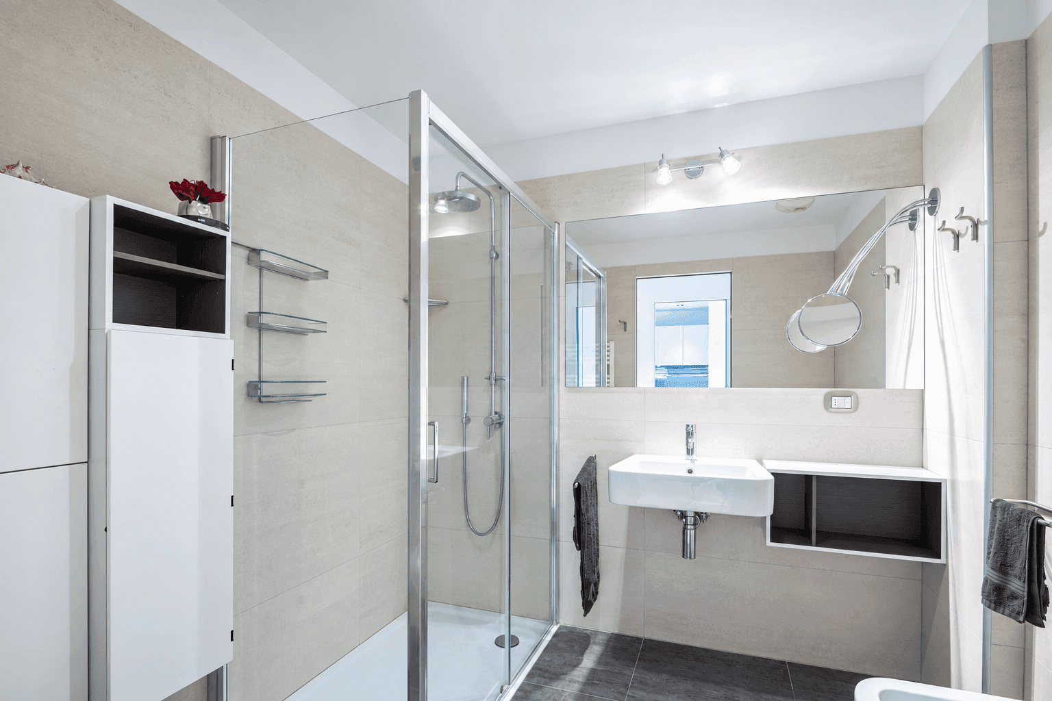 Modernes Badezimmer mit begehbarer Dusche, Wandwaschbecken und großen Fliesen.