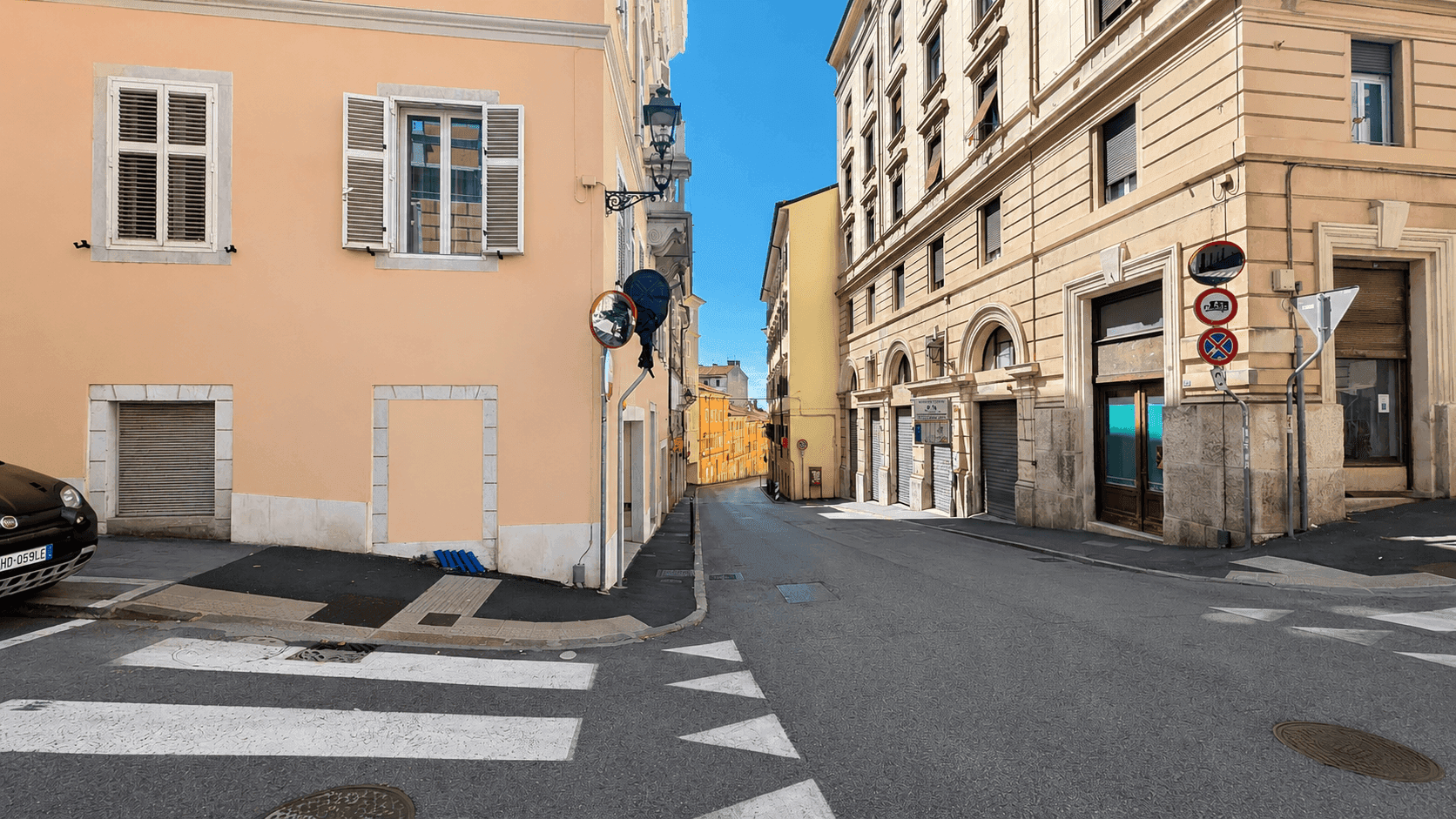 Ruhige Stadtstraße mit historischen Gebäuden und einem Zebrastreifen, der zum Überqueren einlädt.