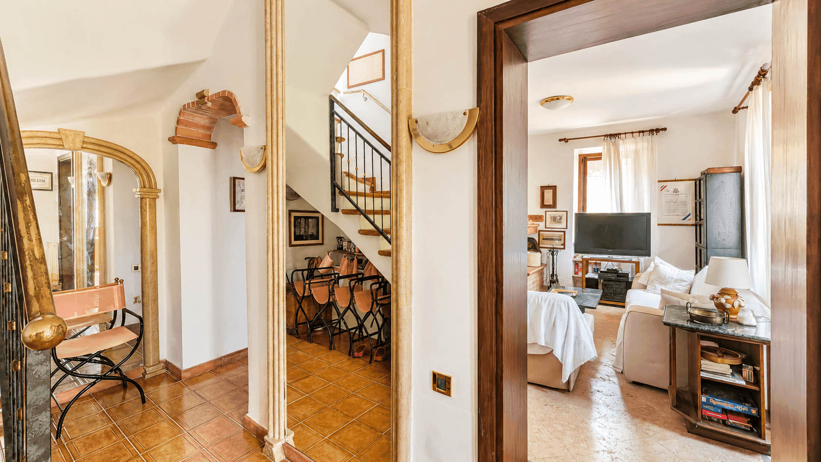 Heller Eingangsbereich mit Terrakottafliesen, Treppe und Blick in das angrenzende Wohnzimmer.