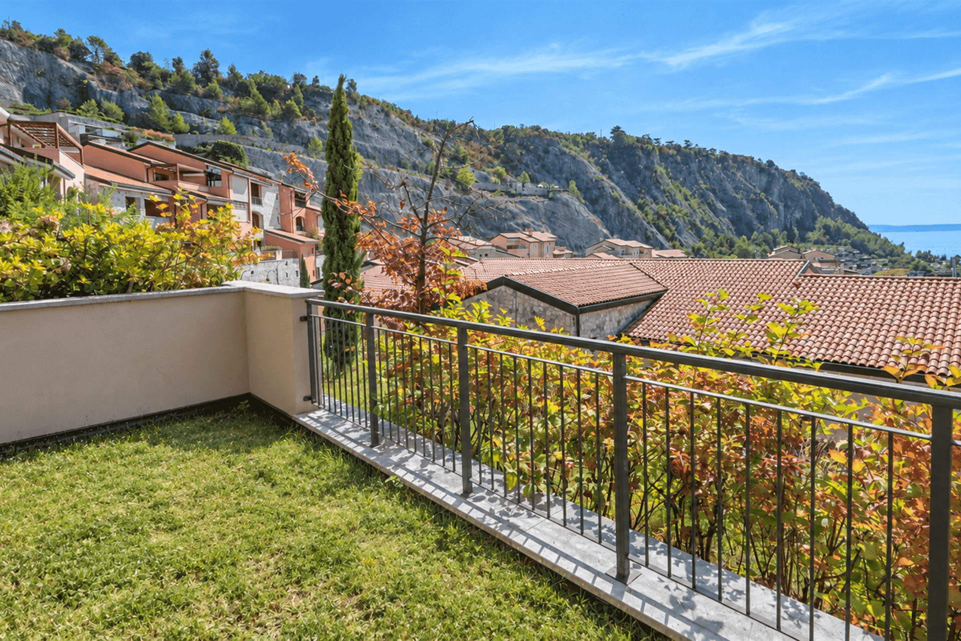 Gepflegter Gartenbereich mit Rasen und weitem Blick auf die umliegende Landschaft und das Meer.