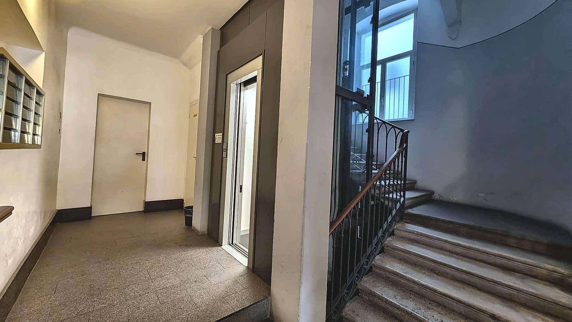 Eingangsbereich mit Aufzug, Treppe und traditionellem Design, das den Charme des Gebäudes unterstreicht.