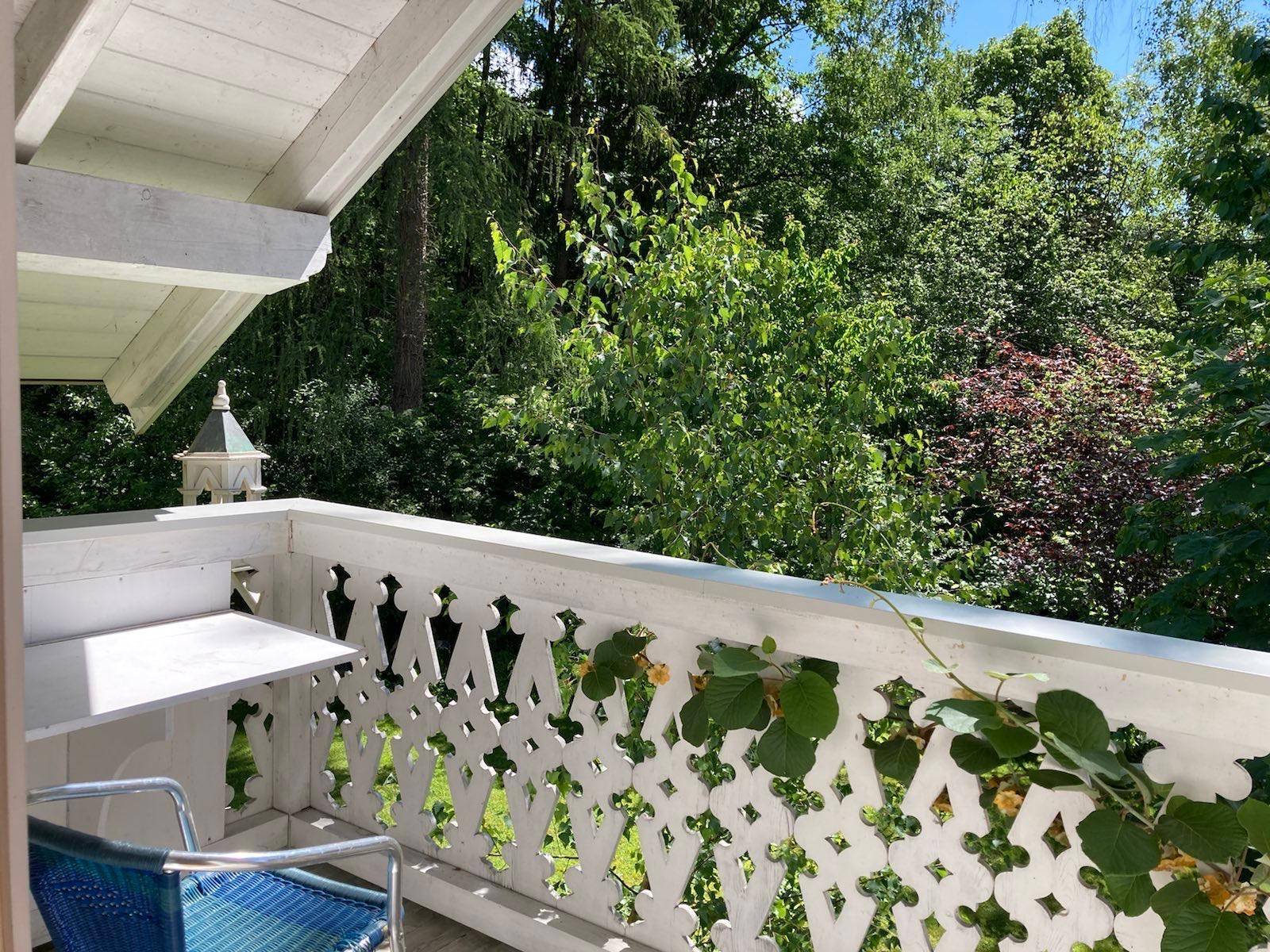 Kleiner Balkon mit dekorativem Geländer und üppigem Grünblick, ideal für entspannte Momente im Freien.