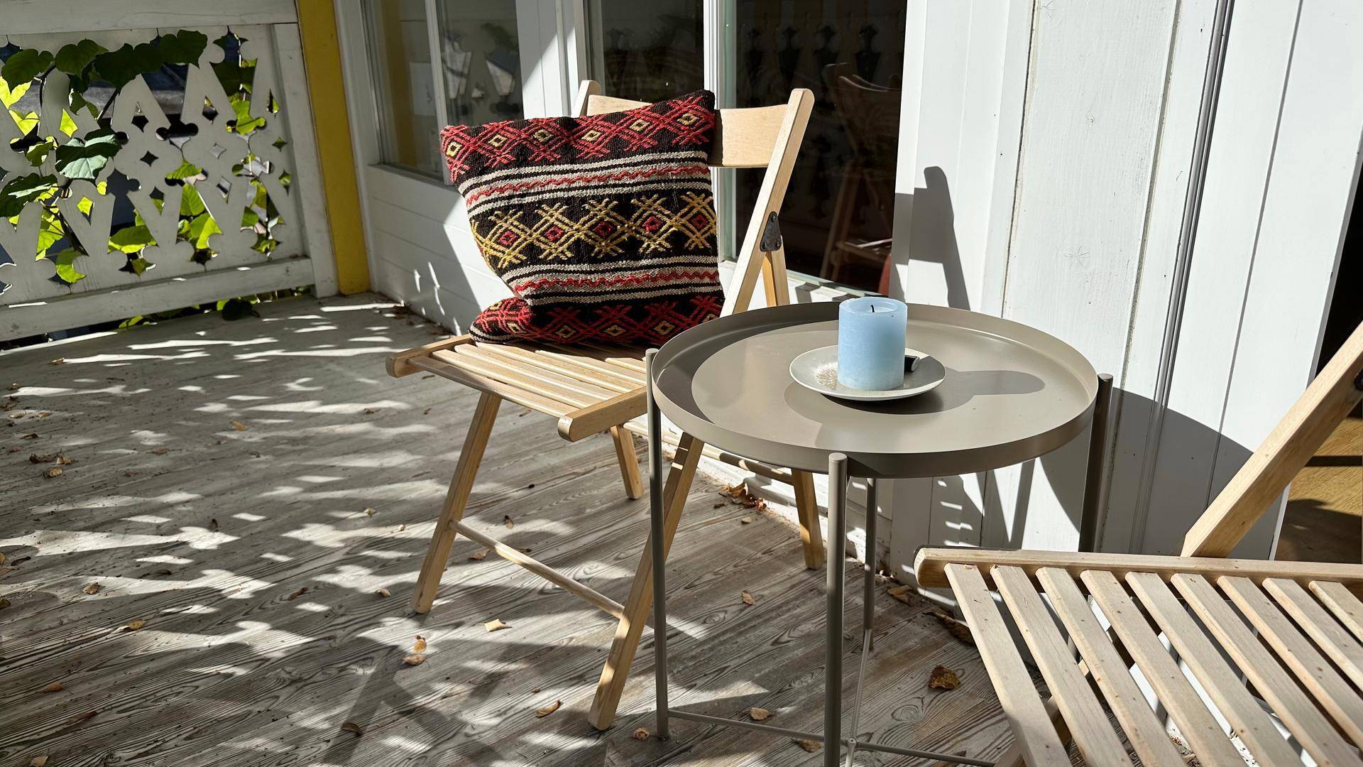 Sonniger Terrassenbereich mit Holzmöbeln und einem kleinen Tisch, perfekt für Mahlzeiten im Freien.