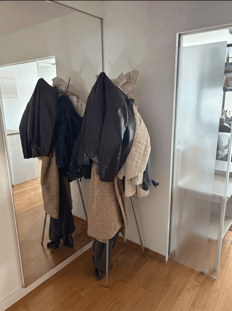 Flur mit großem Spiegel, Garderobe und einer modernen Schiebetür aus Milchglas.