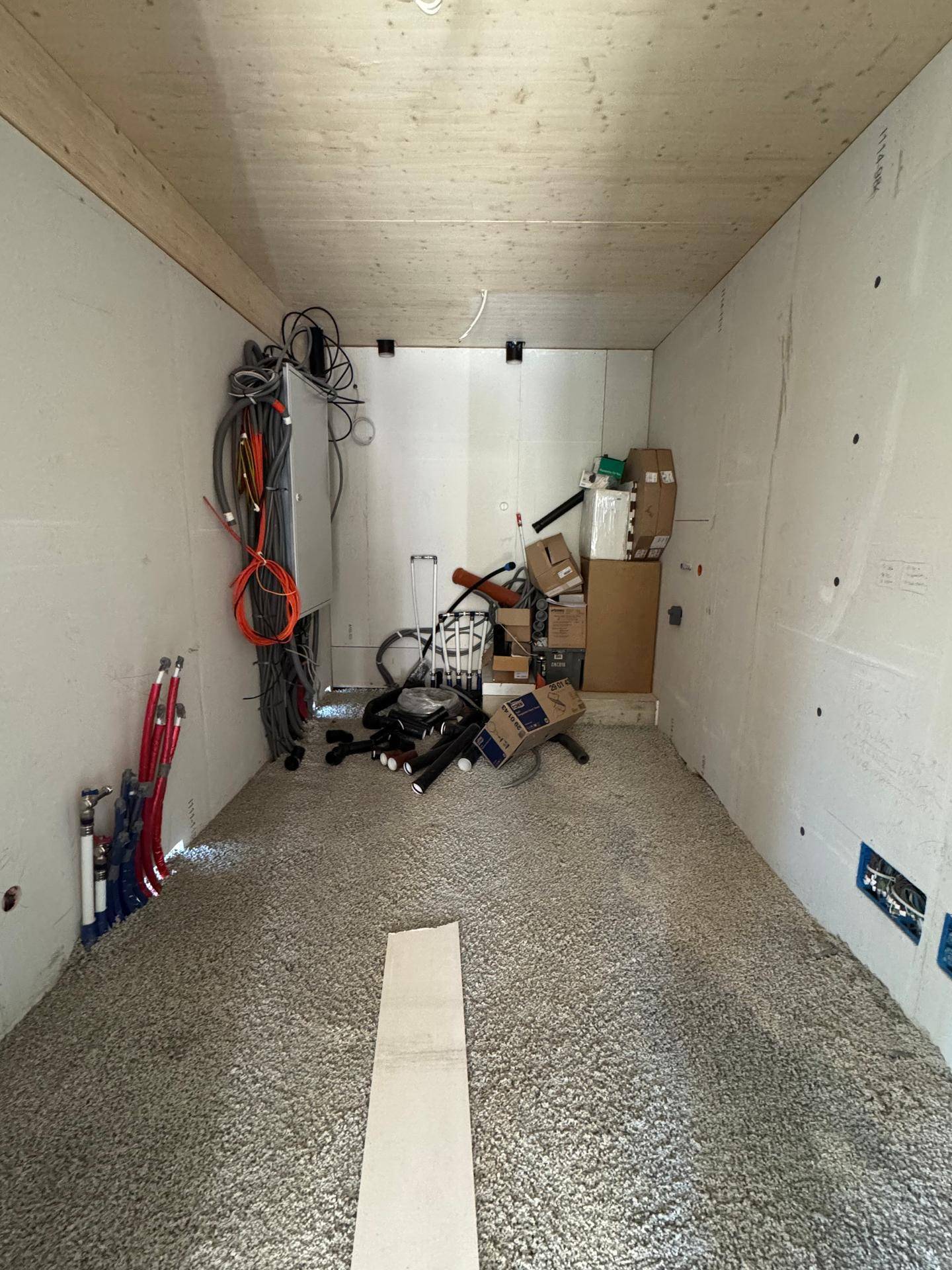 Hauswirtschaftsraum im Rohbau mit vielen Kabeln, Installationen und vorbereitetem Estrichboden.