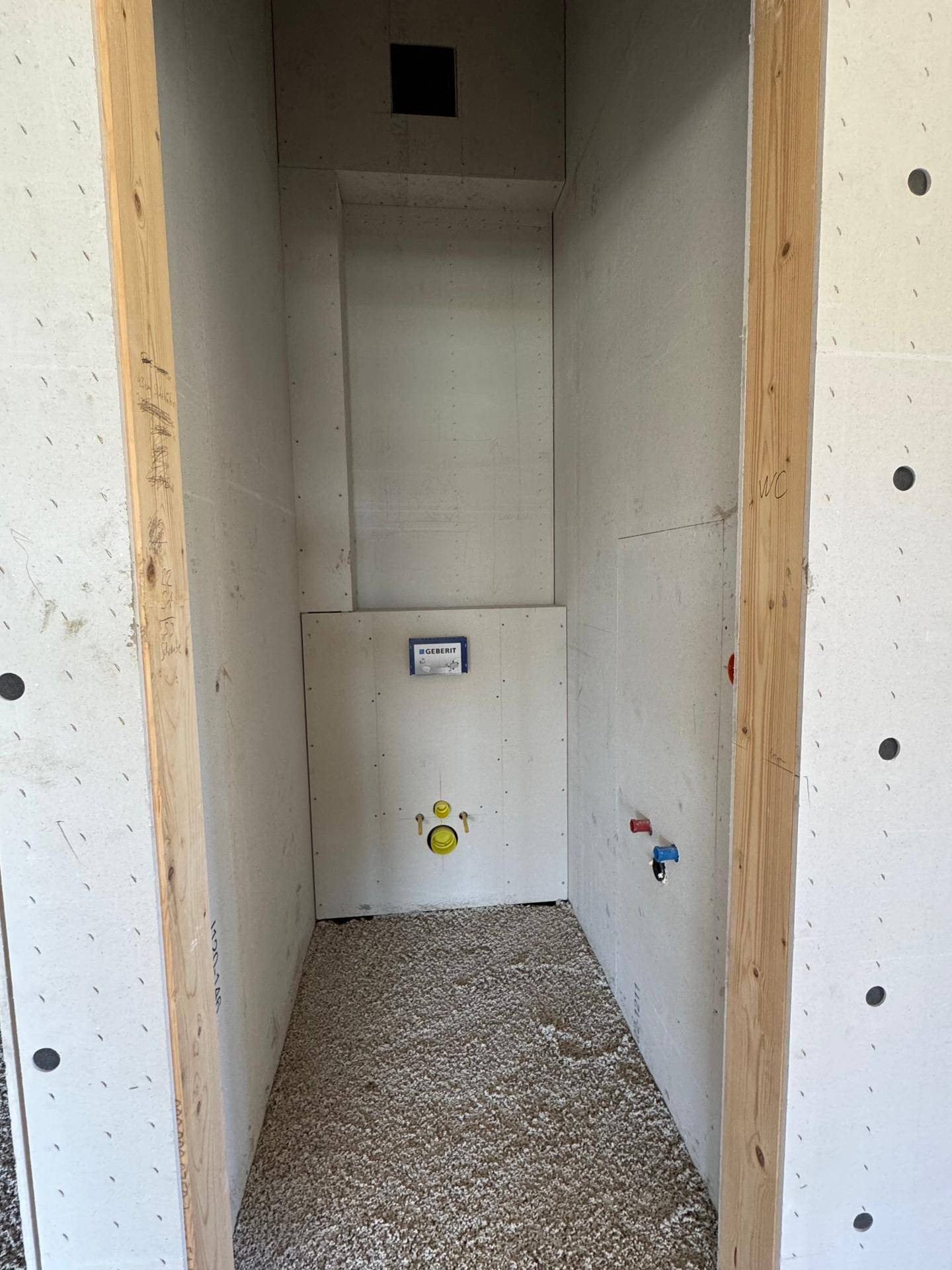 Kleiner Raum im Rohbau mit Vorinstallation für eine Wandtoilette und Estrichboden.