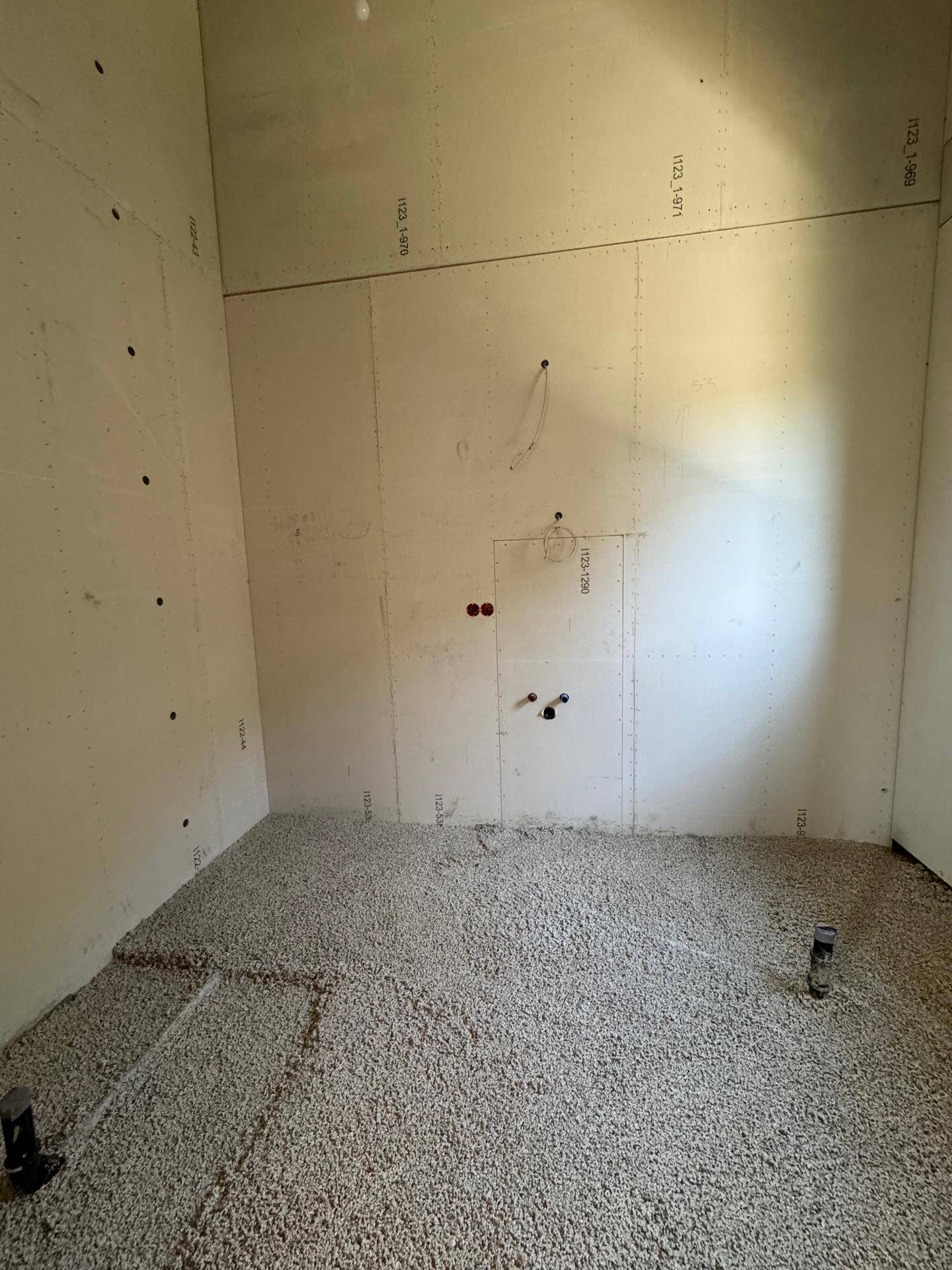 Badezimmer im Rohbau mit vorbereiteten Anschlüssen für Sanitärinstallationen.