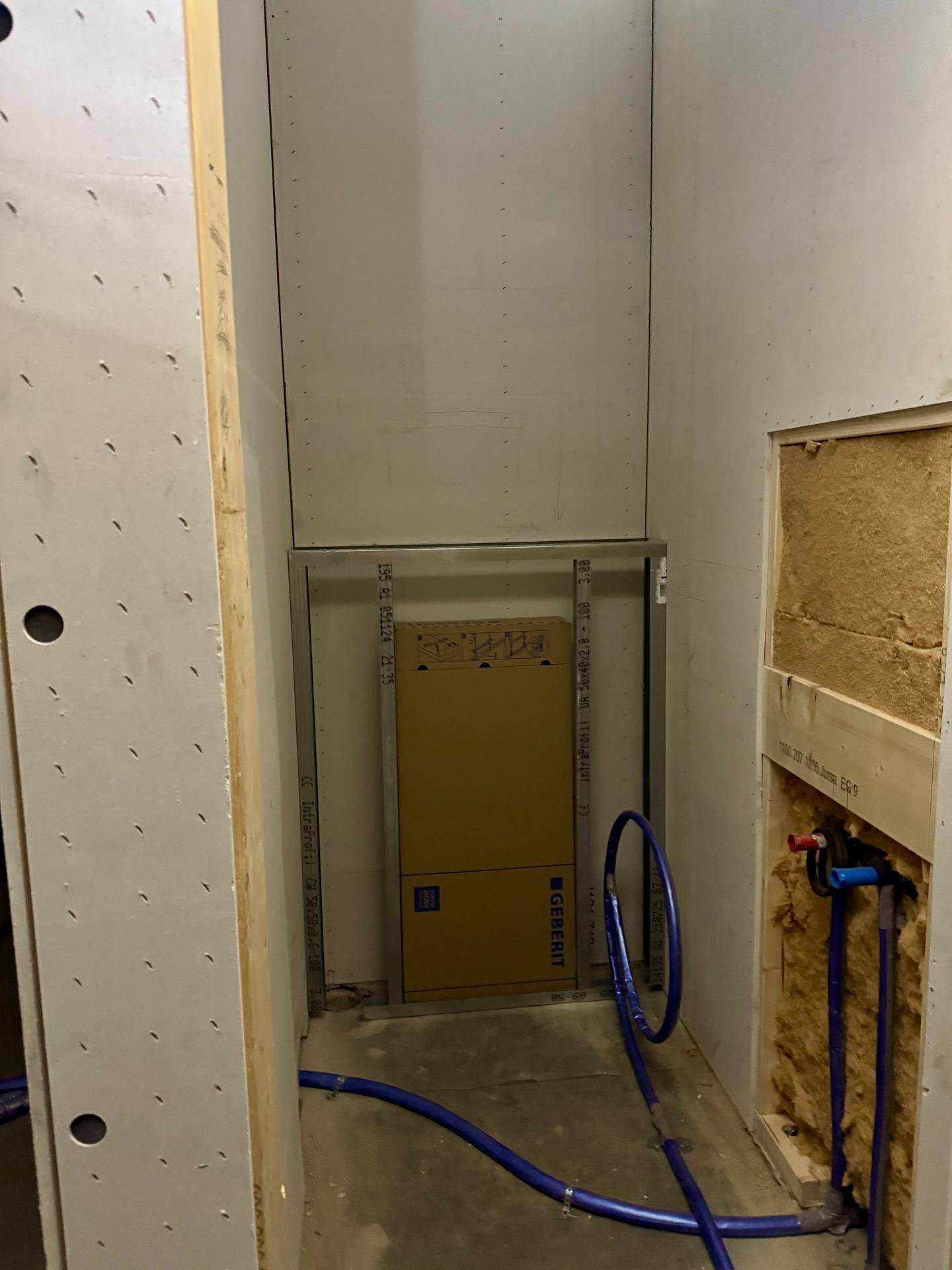 Kleiner Raum im Rohbau mit vorbereiteten Installationen für ein Wand-WC.