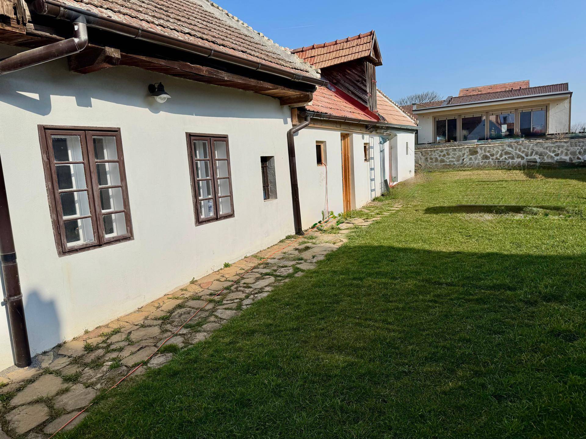 Traditionelles Bauernhaus mit großem Garten und gepflastertem Weg an einem sonnigen Tag.