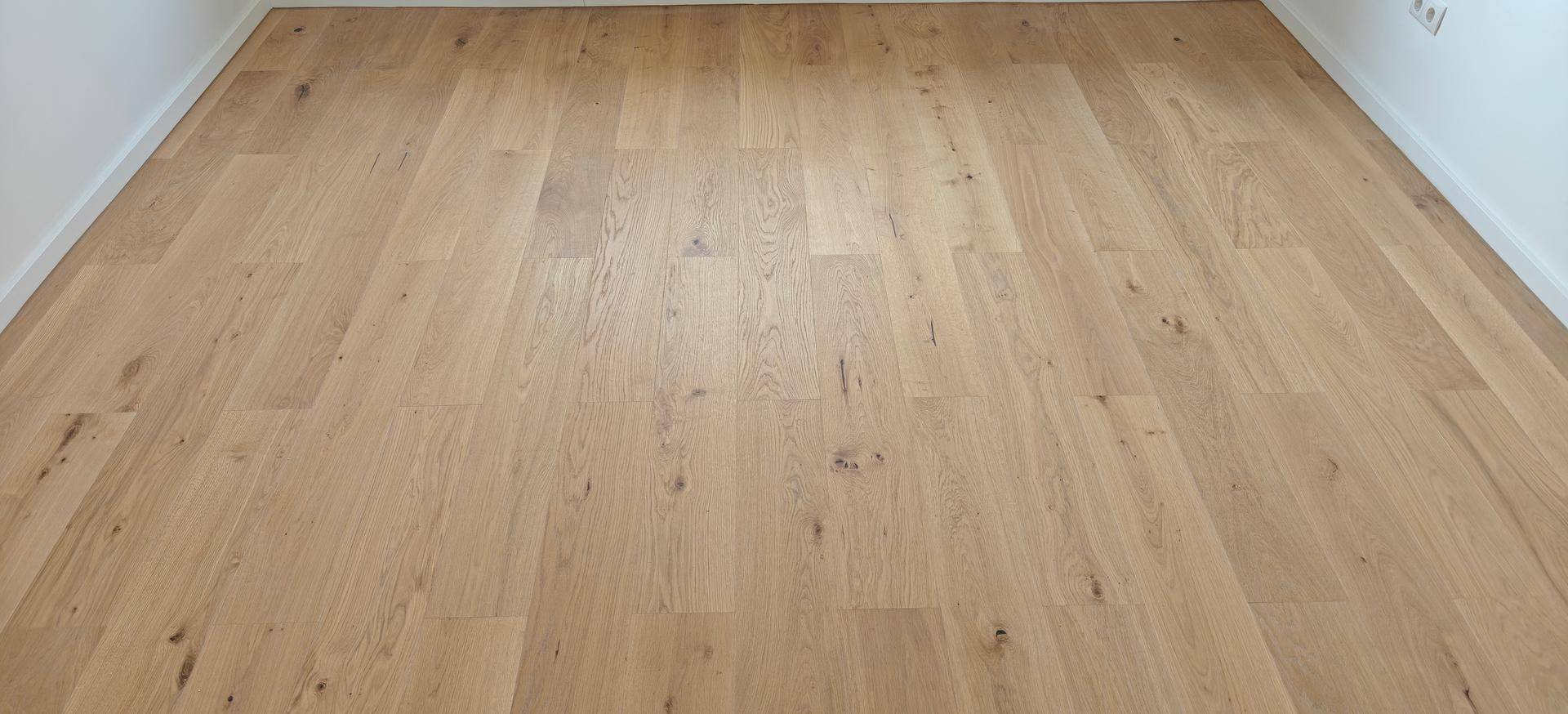 Detailaufnahme eines hochwertigen Holzbodens mit natürlicher Maserung und warmer Farbgebung.