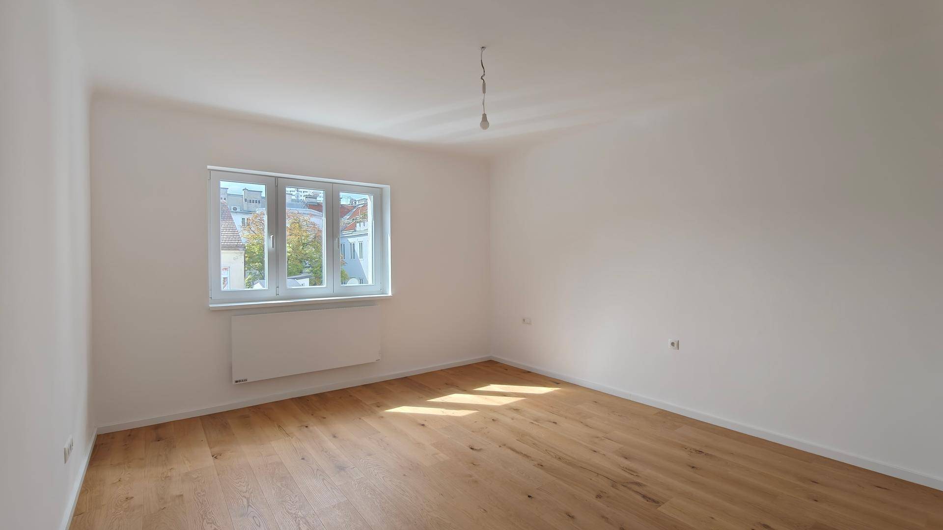 Leeres Zimmer mit Parkettboden und großen Fenstern, ideal für neue Einrichtungsideen.