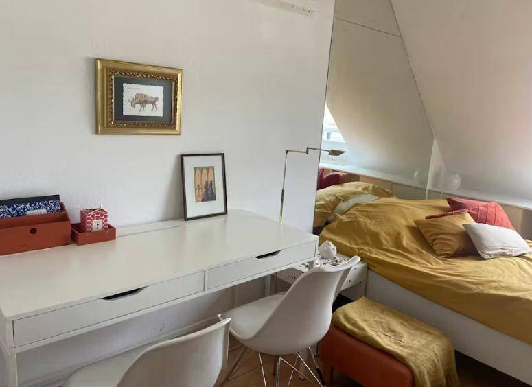 Arbeitsbereich im Schlafzimmer mit weißem Schreibtisch, Spiegelwand und Holzboden.