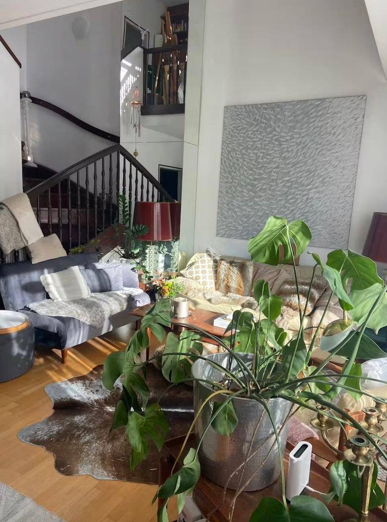 Geräumiges Wohnzimmer mit Holzboden, bequemen Sofas und viel Tageslicht von großen Fenstern.