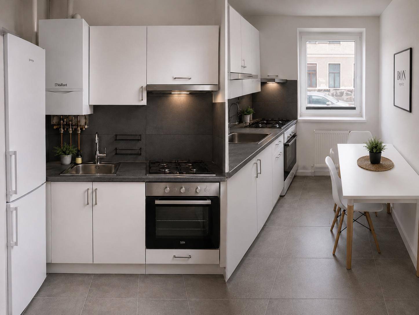 Moderne Einbauküche in Weiß mit Gasherd, Backofen, Kühlschrank und Essbereich am Fenster.