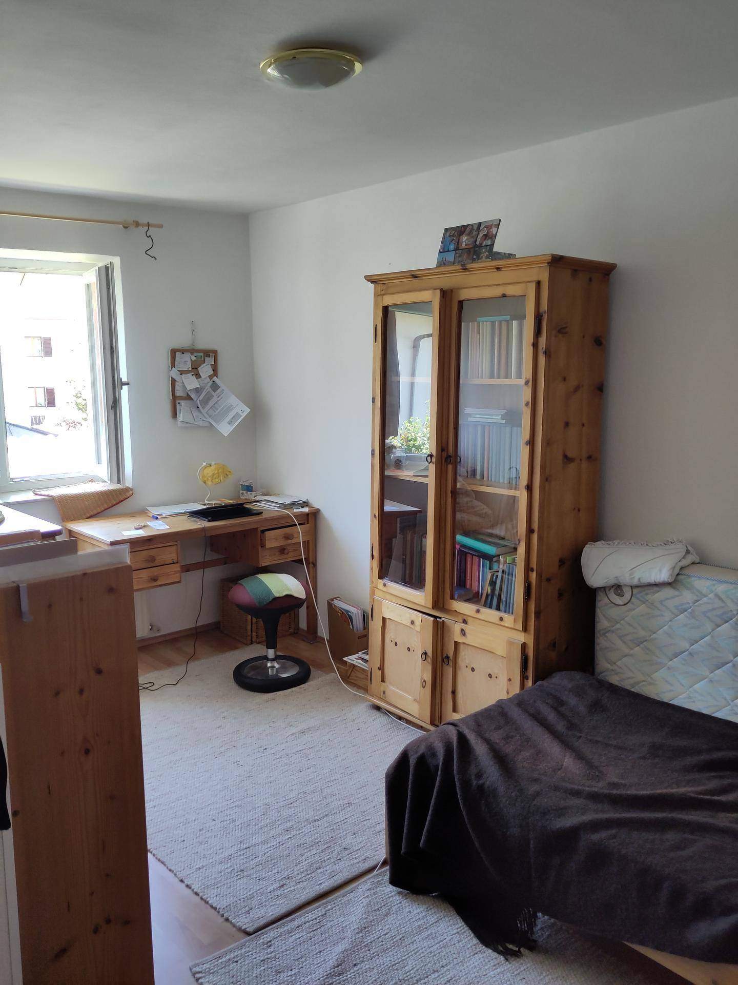 Gemütliches Schlafzimmer mit Holzmöbeln, Schreibtisch und Teppichboden, ideal als Arbeits- oder Gästezimmer.