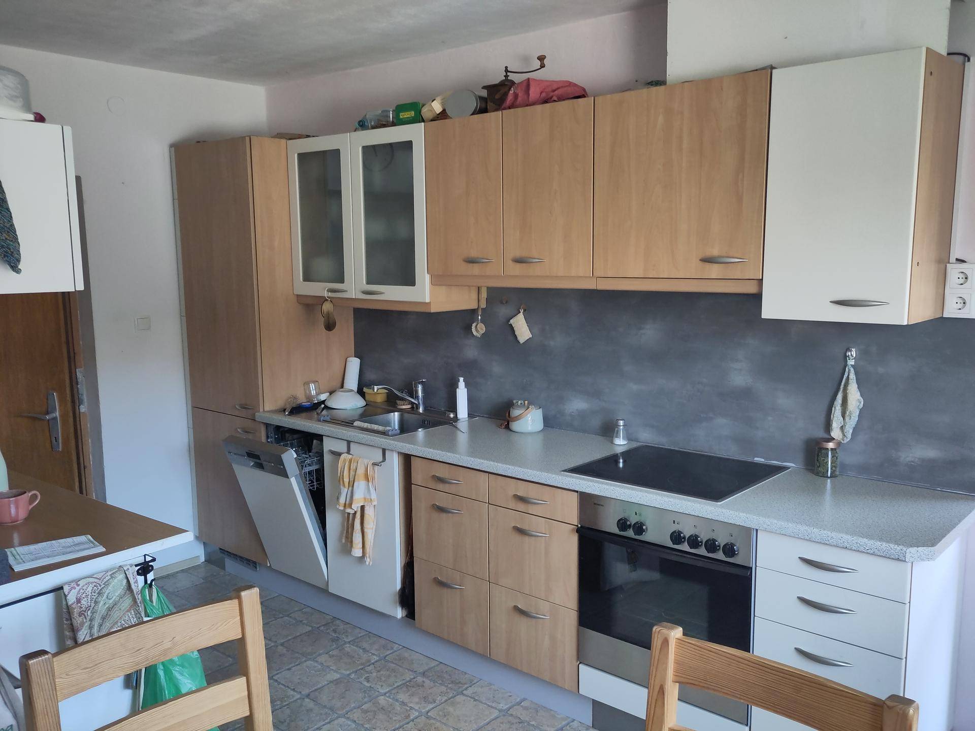 Helle Küche mit Holzschränken, integriertem Geschirrspüler und modernem Kochfeld.