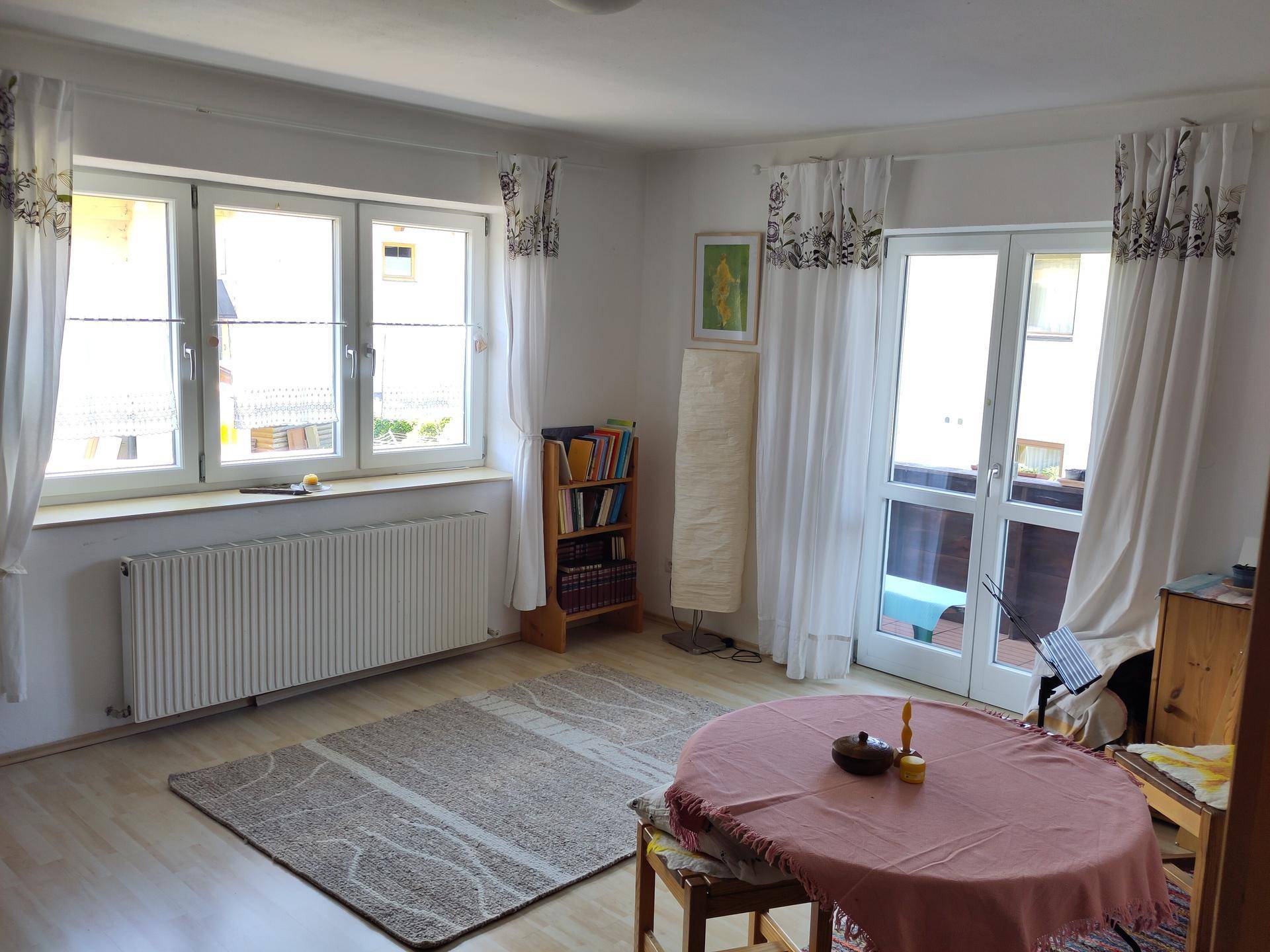 Helles Wohnzimmer mit Laminatboden, großen Fenstern und direktem Zugang zum Balkon.