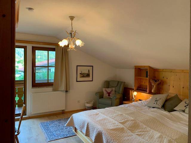 Helles Schlafzimmer im Dachgeschoss mit Holzbalken und Balkonzugang.