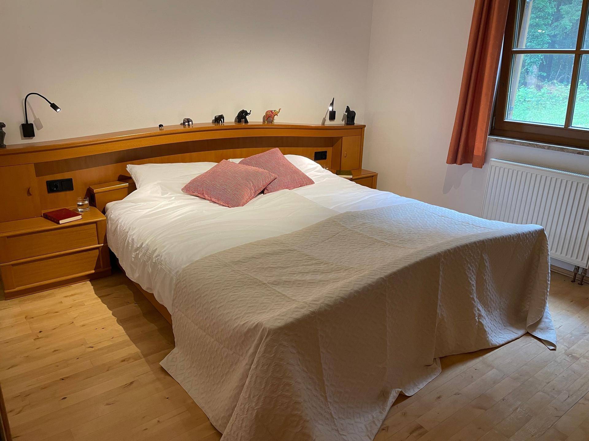 Gemütliches Schlafzimmer mit Doppelbett, Holzmöbeln und Parkettboden.