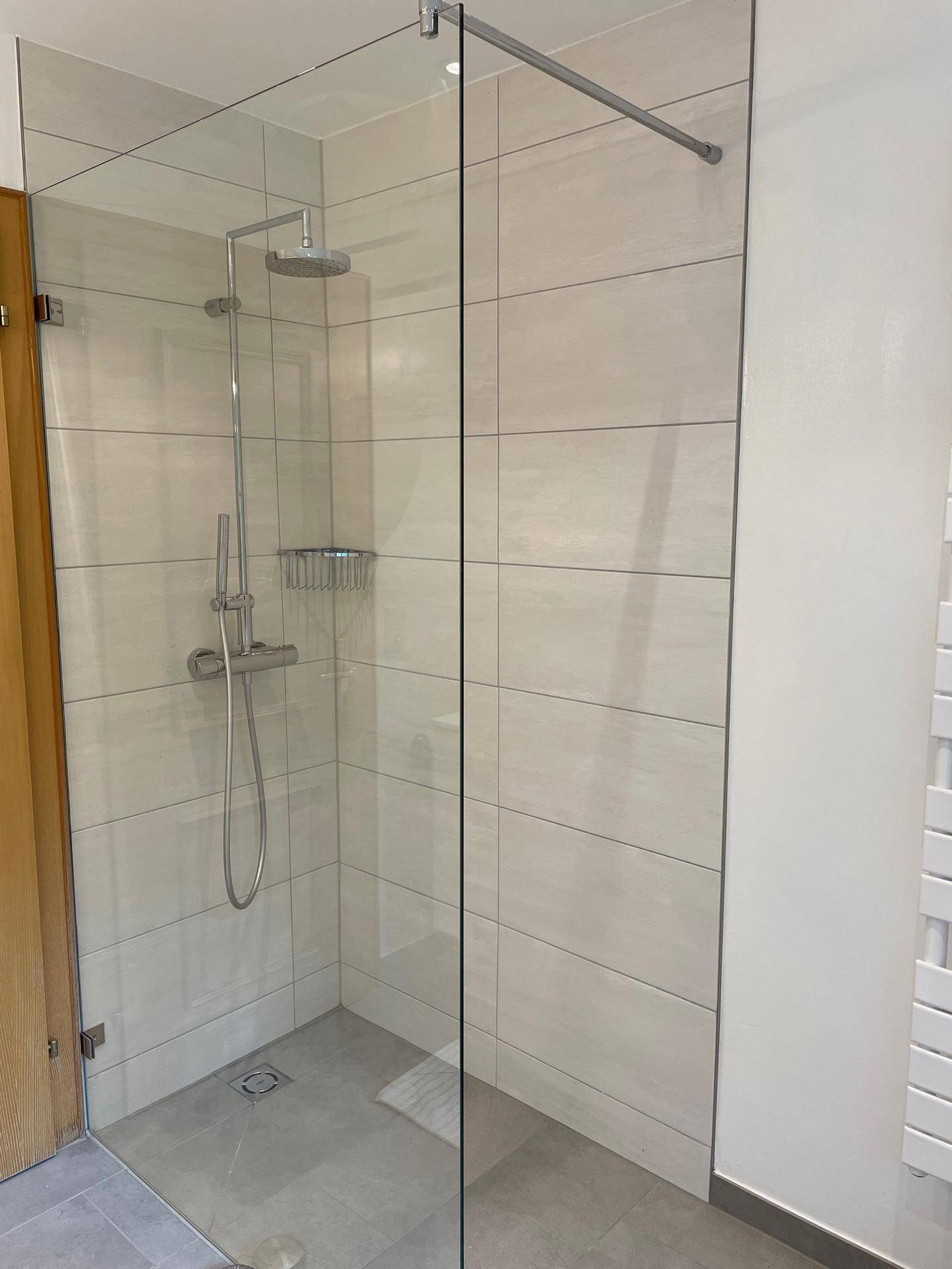 Modernes Badezimmer mit ebenerdiger Dusche und hellen Fliesen.