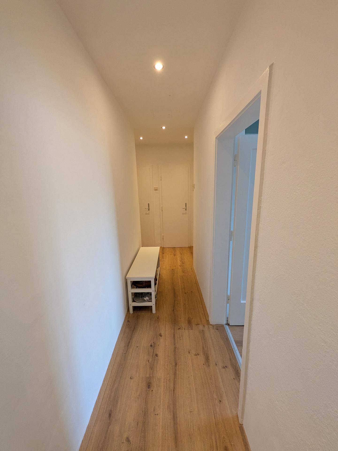 Heller Flur mit Laminatboden, Einbaustrahlern und praktischer Schuhbank.