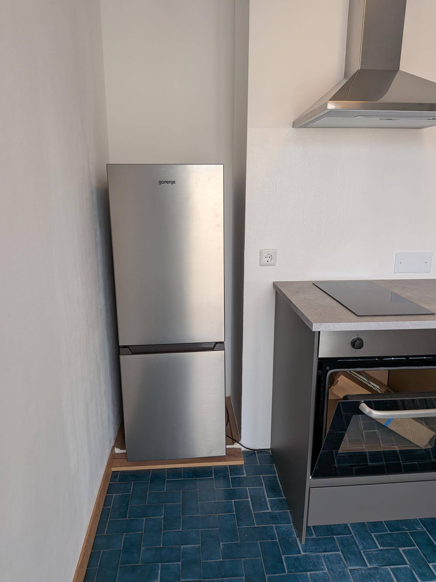 Küchenzeile mit Edelstahlkühlschrank, Induktionskochfeld und Backofen.