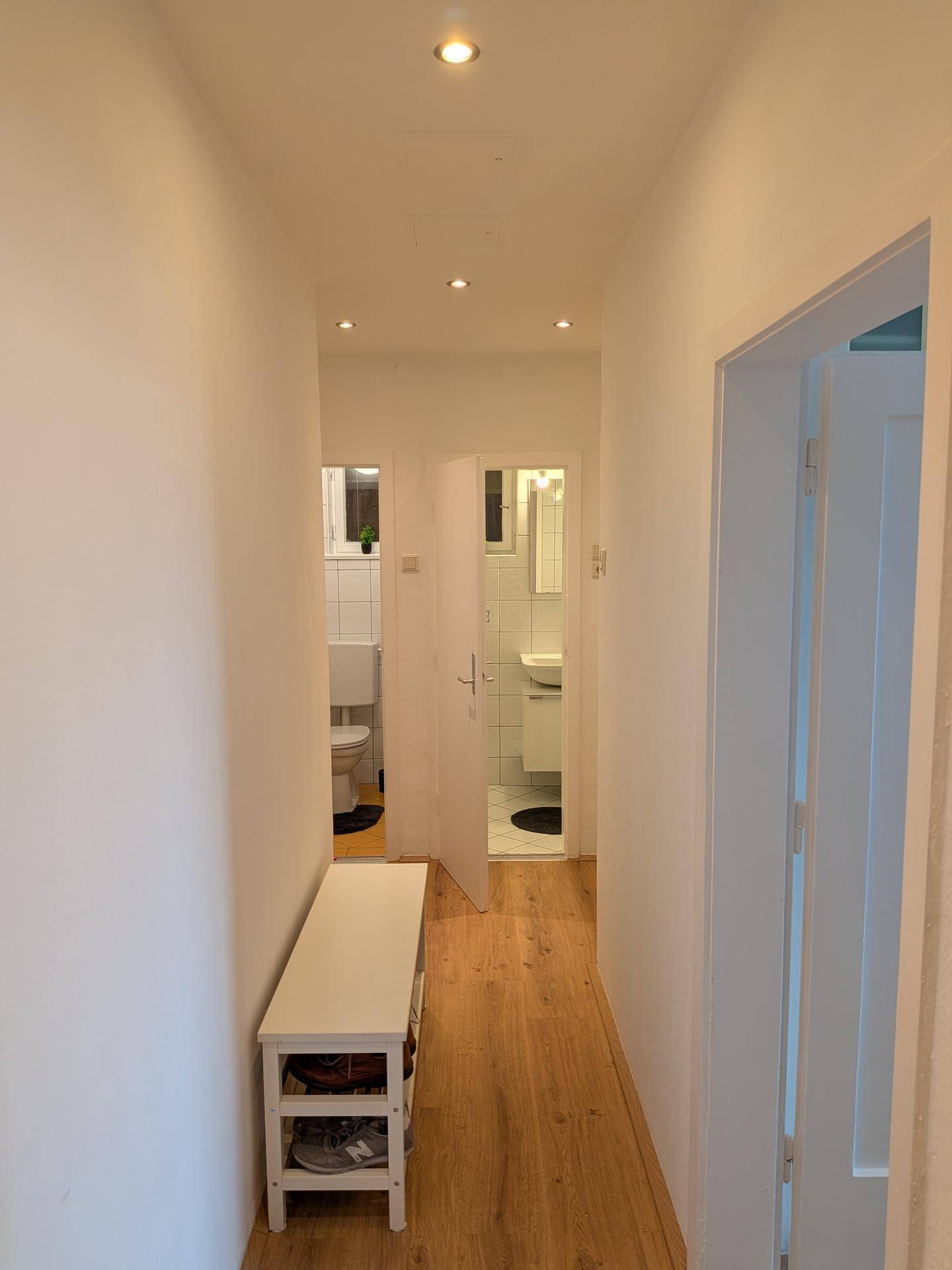 Flur mit Laminatboden und Zugang zu Badezimmer und separatem WC.