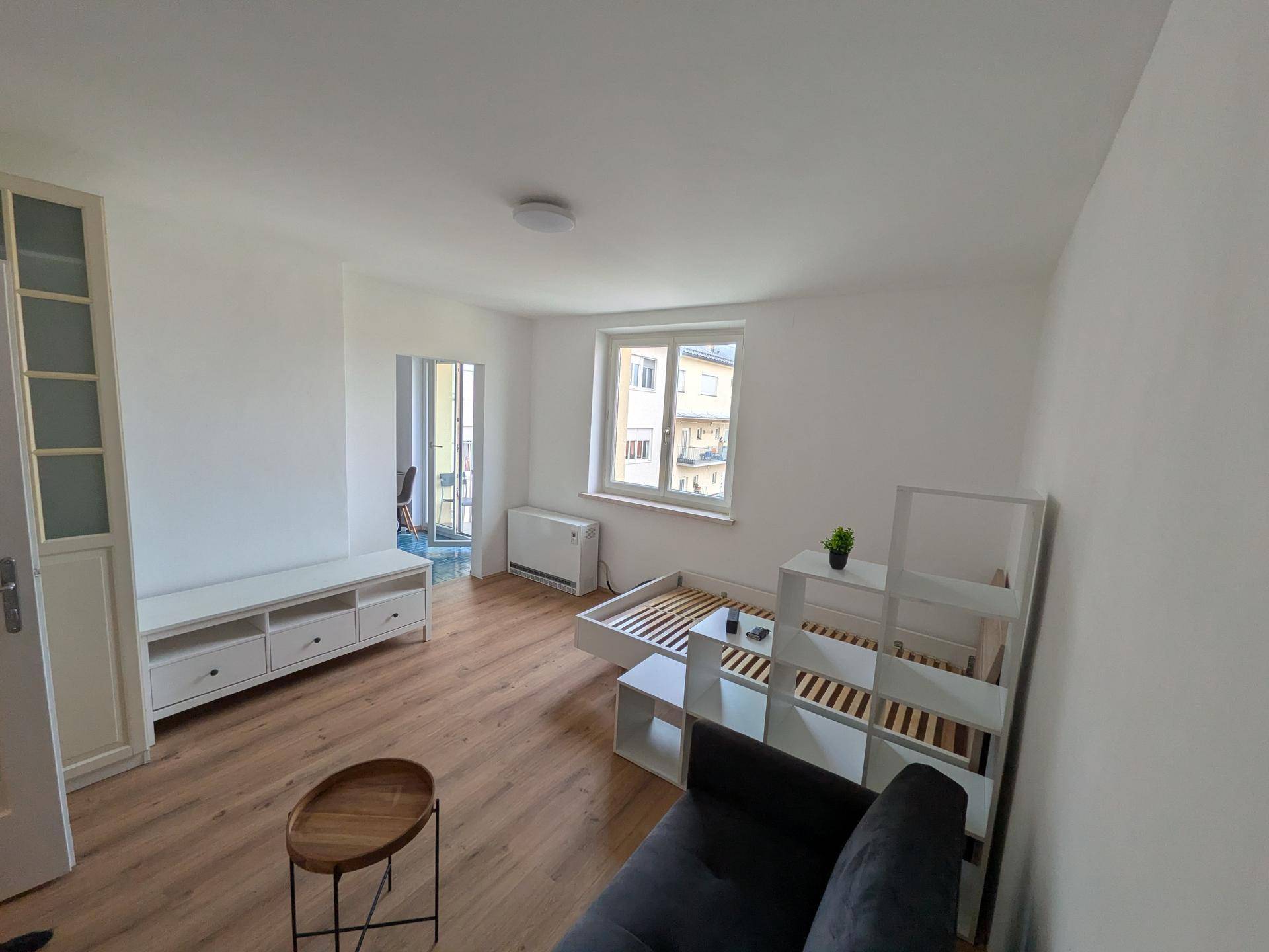 Heller Wohnbereich mit Laminatboden, großem Fenster und Blick auf die Umgebung.