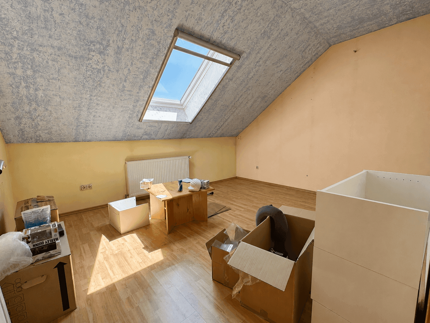 Leeres Dachgeschosszimmer mit Dachfenster, schrägen Wänden und Holzboden, bereit zur individuellen Gestaltung.