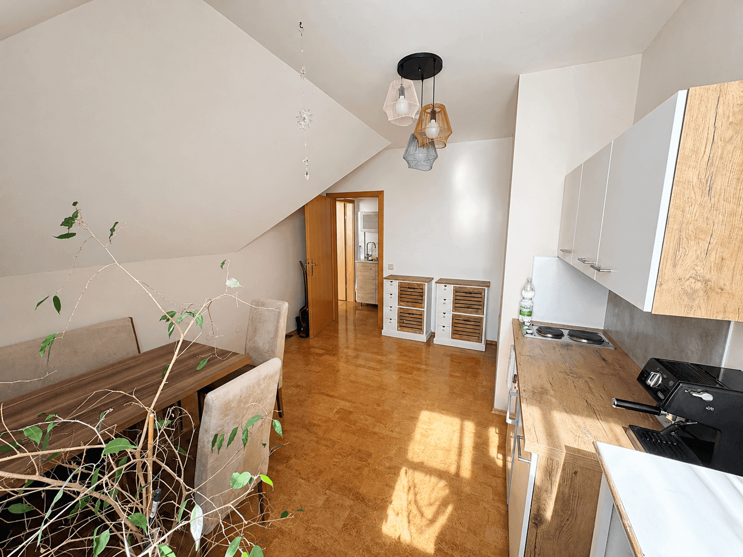 Kleine Küche mit Essbereich im Dachgeschoss, Holzboden und modernen Hängeschränken.