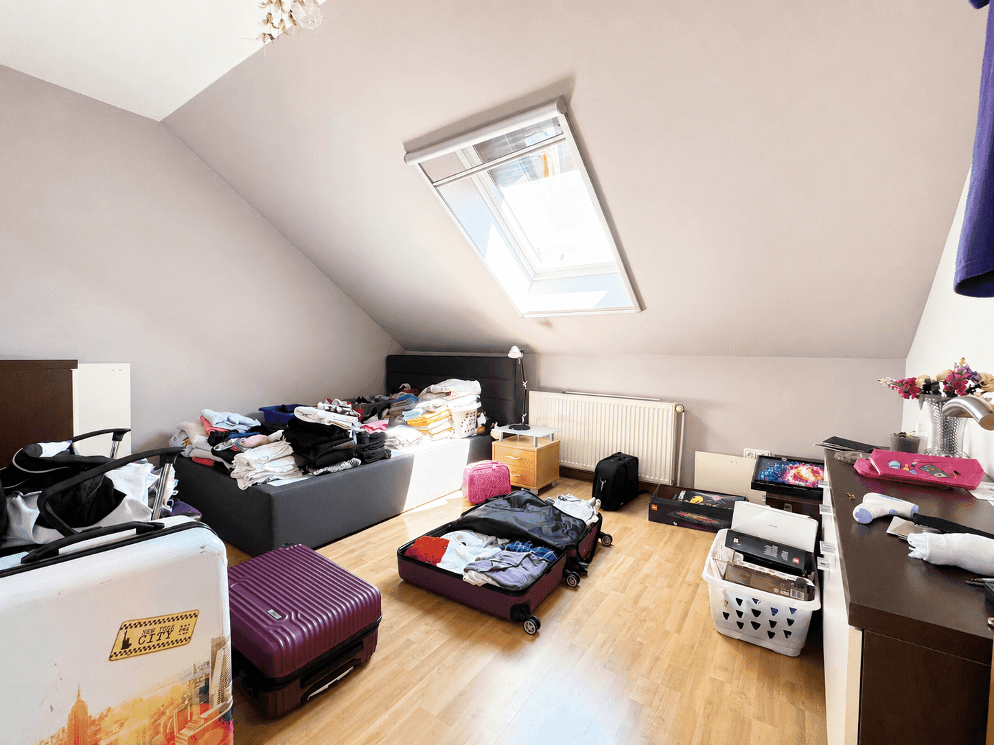 Dachgeschoss-Schlafzimmer mit Dachfenster, schrägen Wänden und Holzboden, derzeit als Abstellraum genutzt.