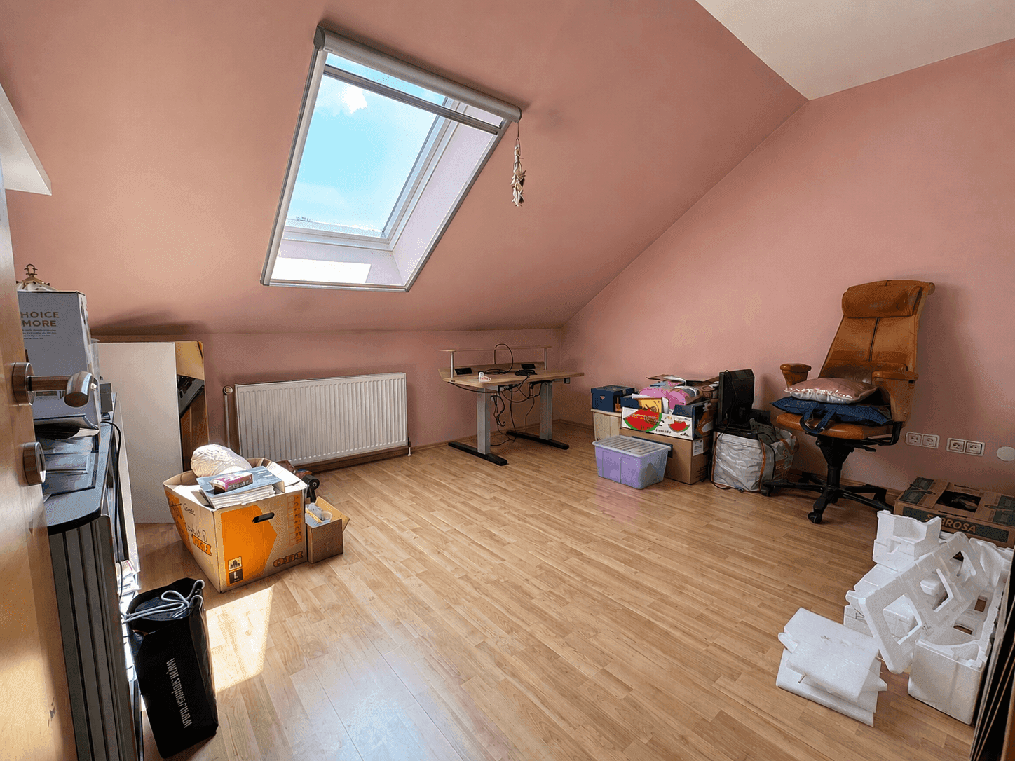 Dachgeschosszimmer mit Dachfenster, schrägen Wänden und Holzboden, ideal als Büro oder Hobbyraum.