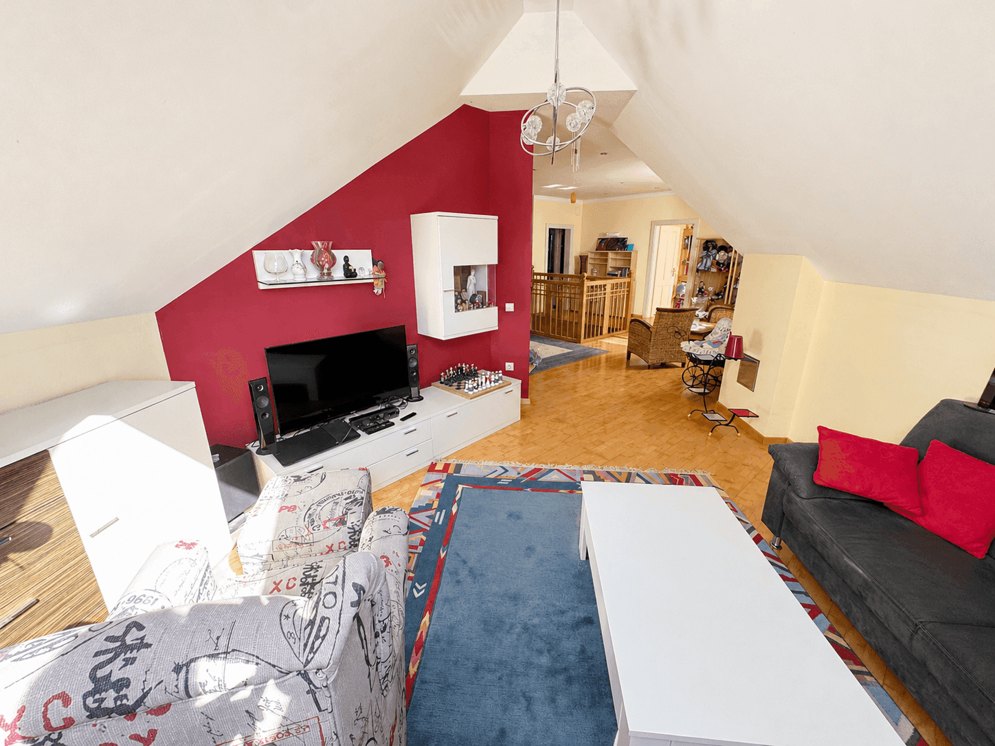 Gemütliches Wohnzimmer im Dachgeschoss mit farbiger Wand und Holzboden.