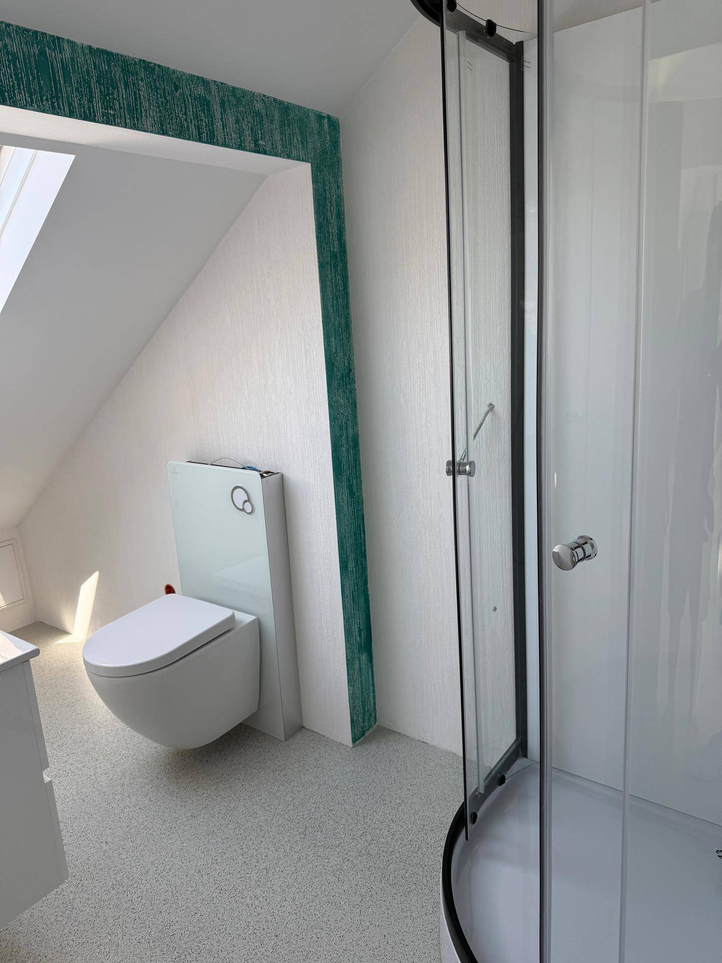 Modernes Badezimmer im Dachgeschoss mit Toilette, Duschkabine und grüner Akzentwand.