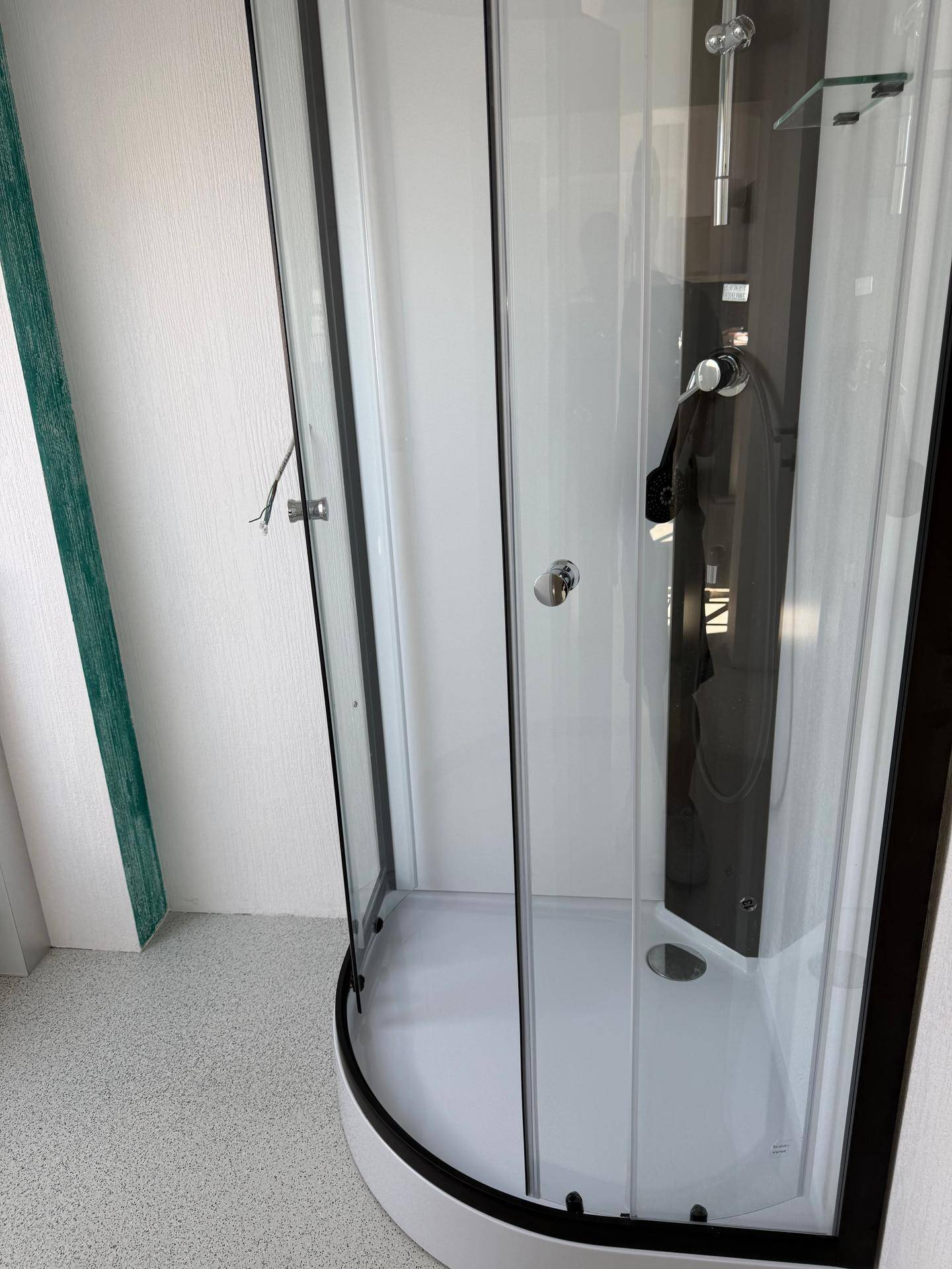 Moderne Duschkabine mit Glaswänden und schwarzem Rahmen in einem Badezimmer.