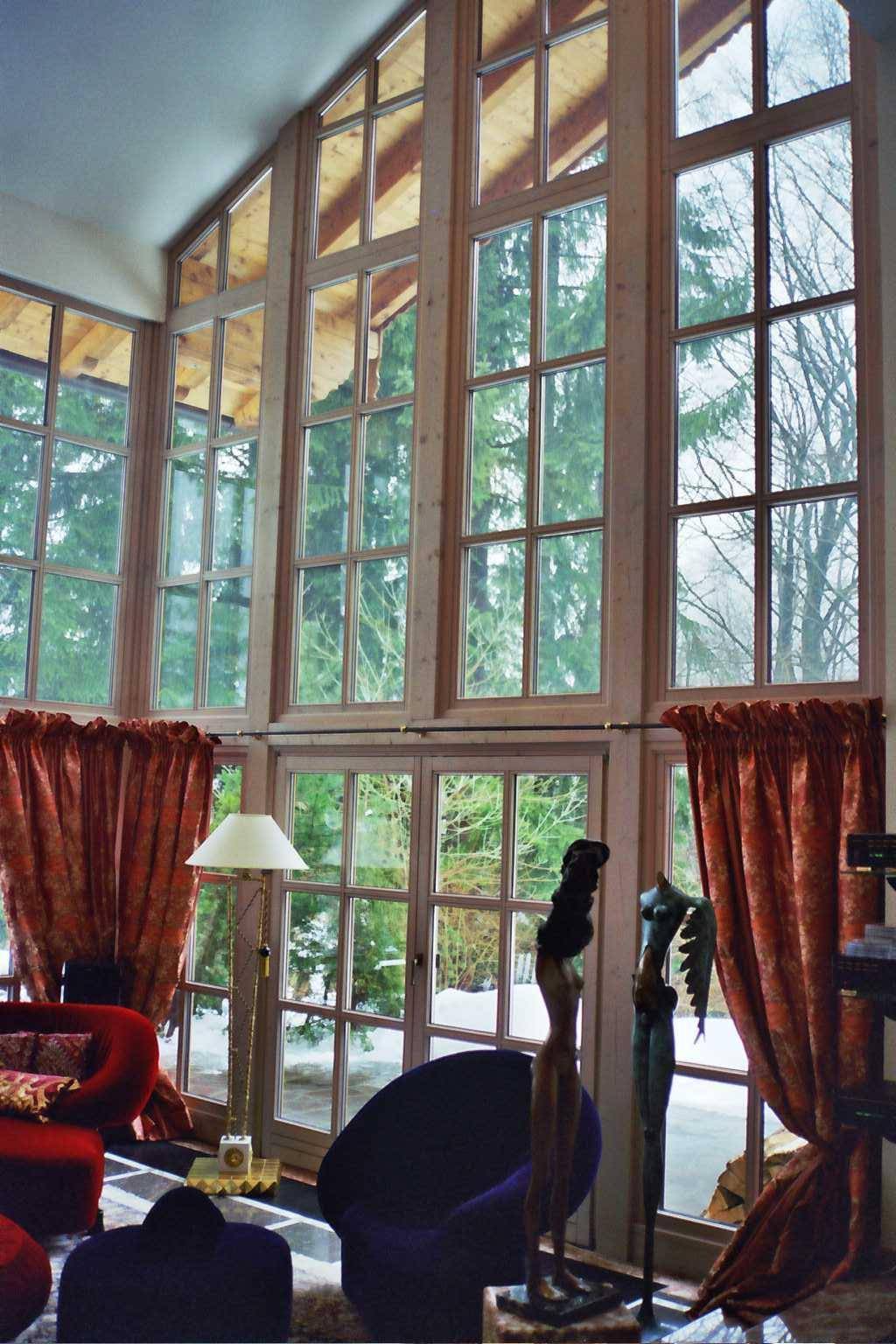 Hohe Fensterfront im Wohnzimmer bietet einen weiten Blick auf die umliegende Natur.