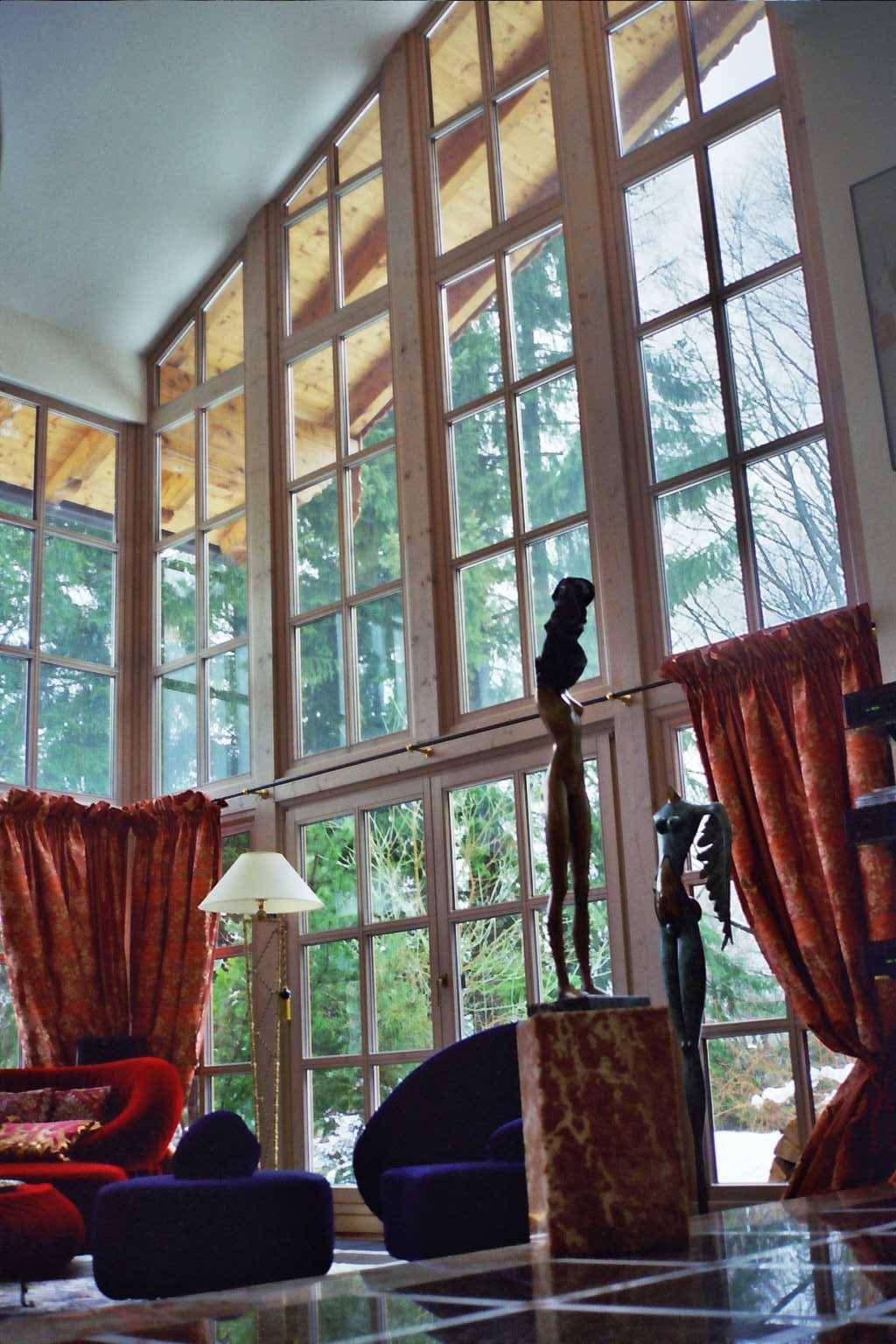 Lichtdurchflutetes Wohnzimmer mit hohen Fenstern und Blick auf die Natur.