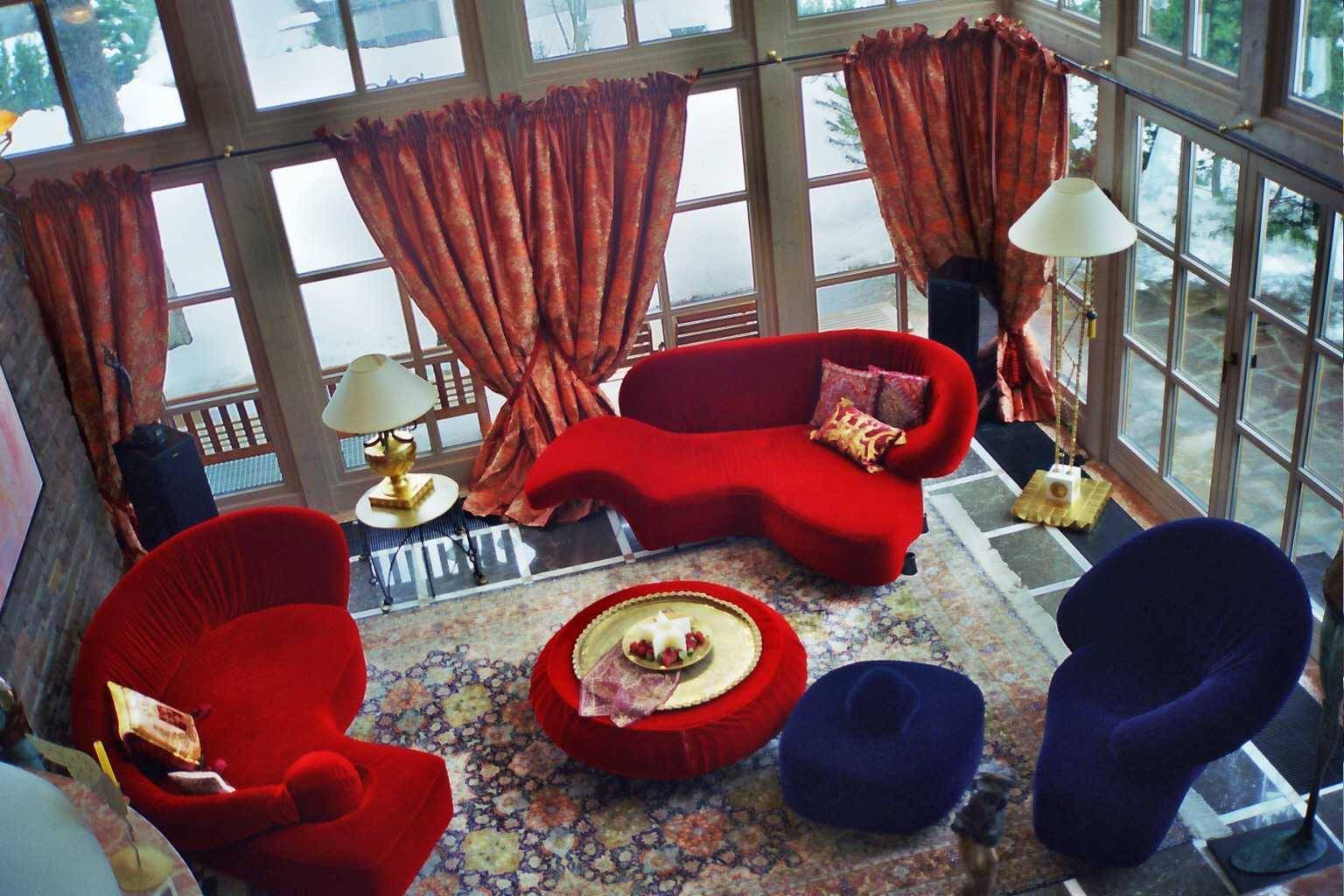 Blick von oben auf das Wohnzimmer mit rotem Sofa, Teppich und großen Fenstern.