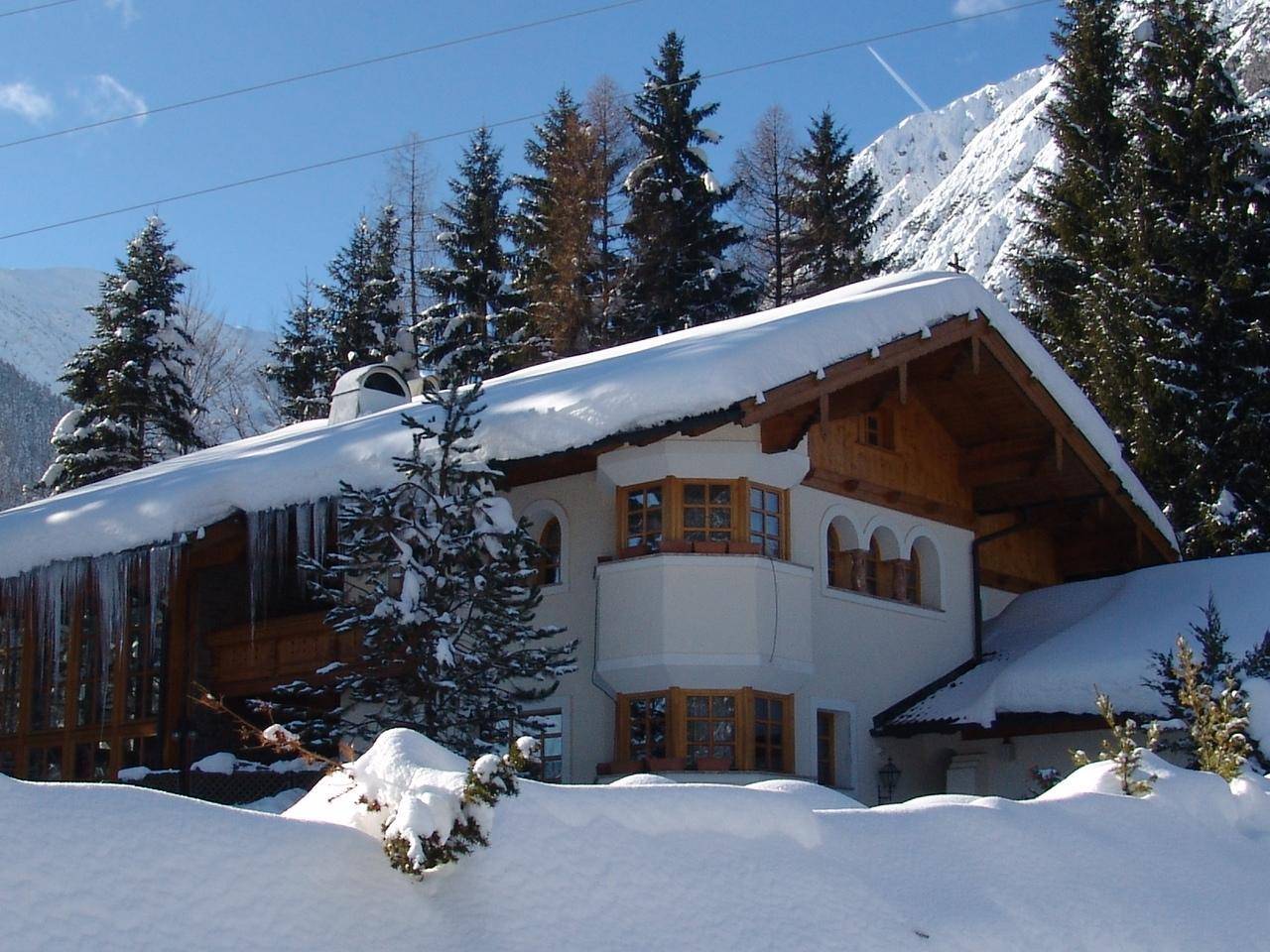 Charmantes Haus im Schnee mit Holzelementen und Blick auf die verschneiten Berge.