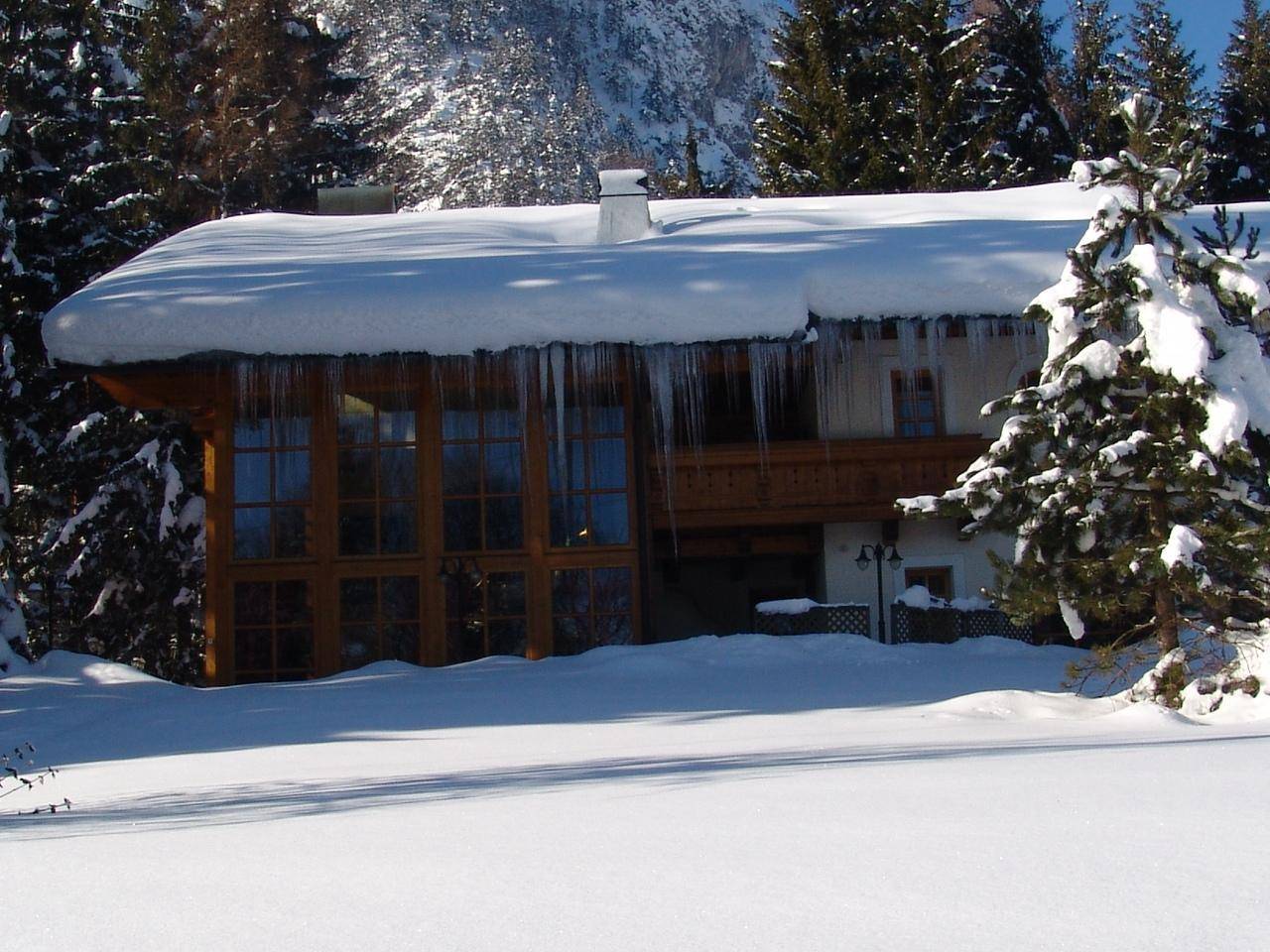 Rückseite des Hauses im Winter mit großen Fenstern und Eiszapfen.