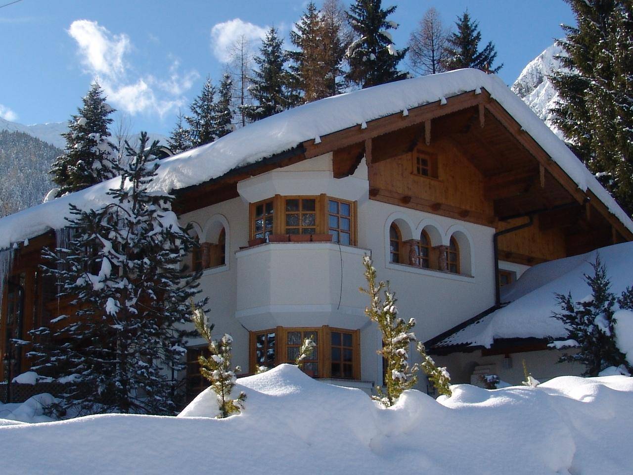Winterliche Ansicht des Hauses mit viel Schnee und blauer Himmel.