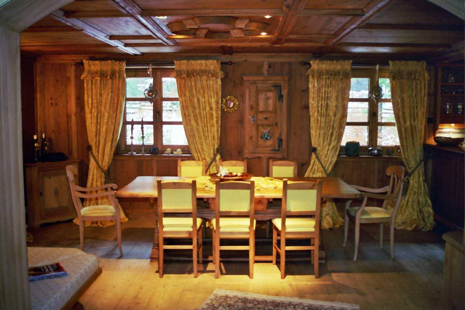 Rustikales Esszimmer mit großem Holztisch, holzgetäfelten Wänden und Decke.