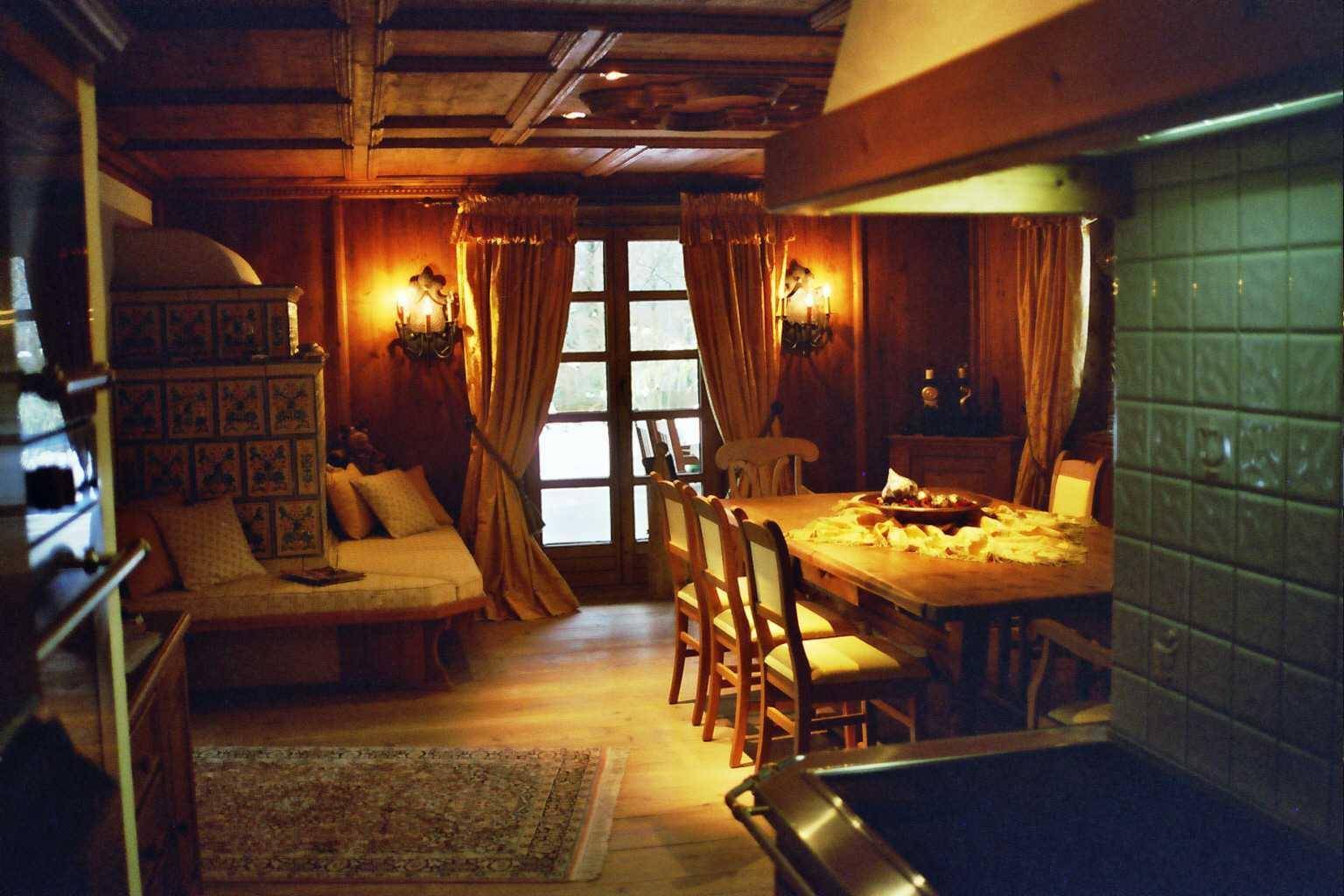 Rustikales Esszimmer mit Holztäfelung, Kachelofen und Zugang zum Außenbereich.
