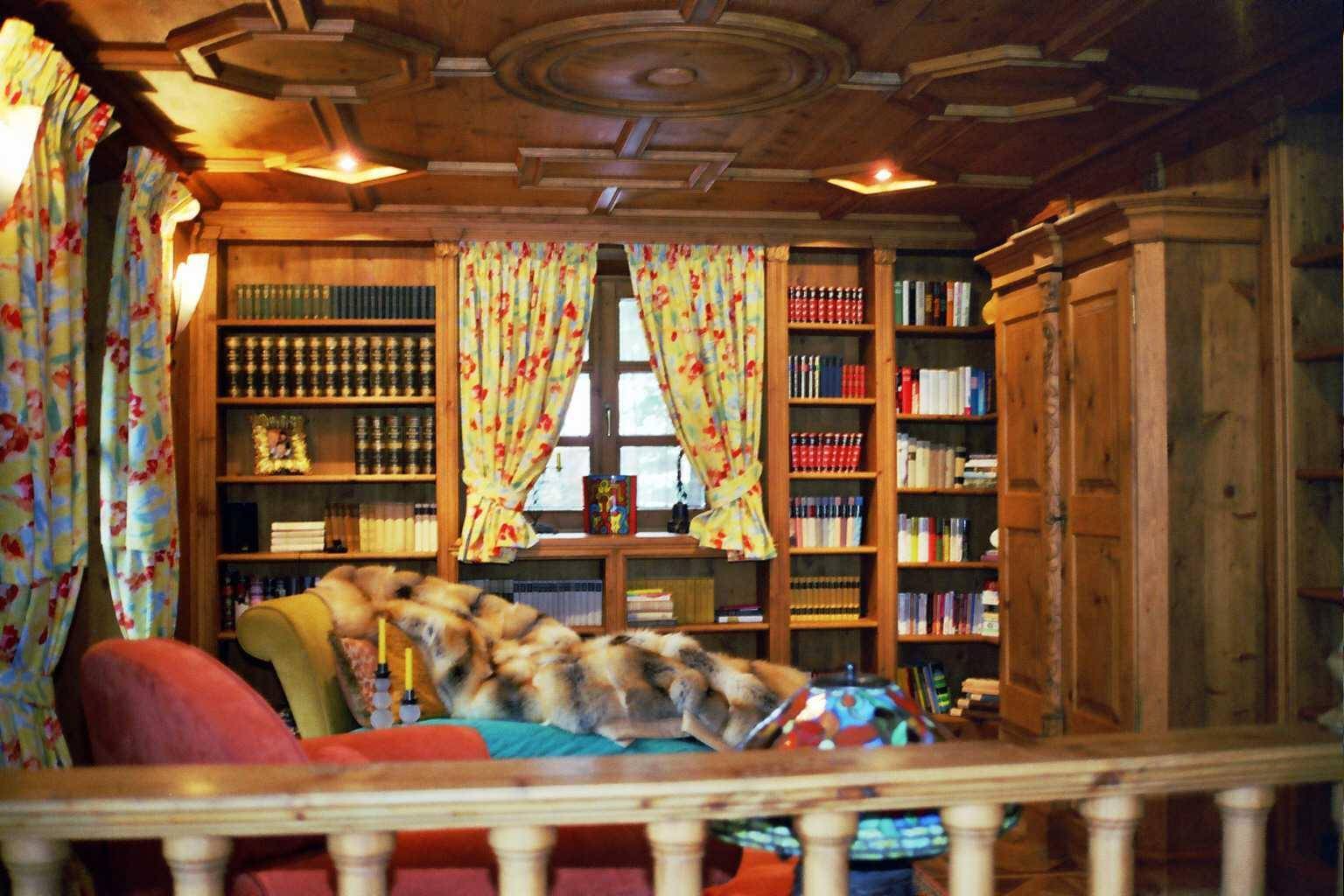 Gemütliche Bibliothek mit holzgetäfelten Wänden, Deckenvertäfelung und eingebauten Bücherregalen.