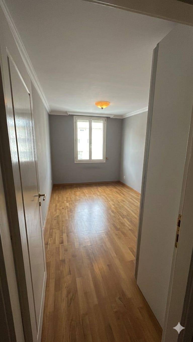Leeres Schlafzimmer mit Holzboden und Fenster für natürliches Licht.