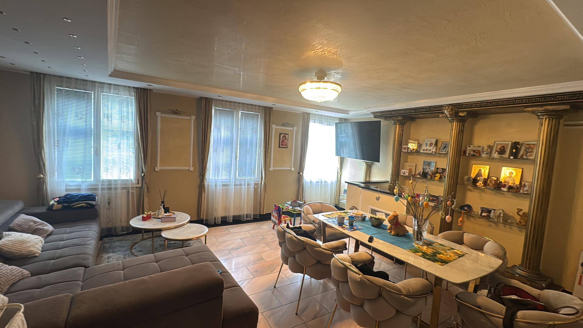 Geräumiger Wohn-Essbereich mit Sofa, Esstisch und dekorativen Säulen.