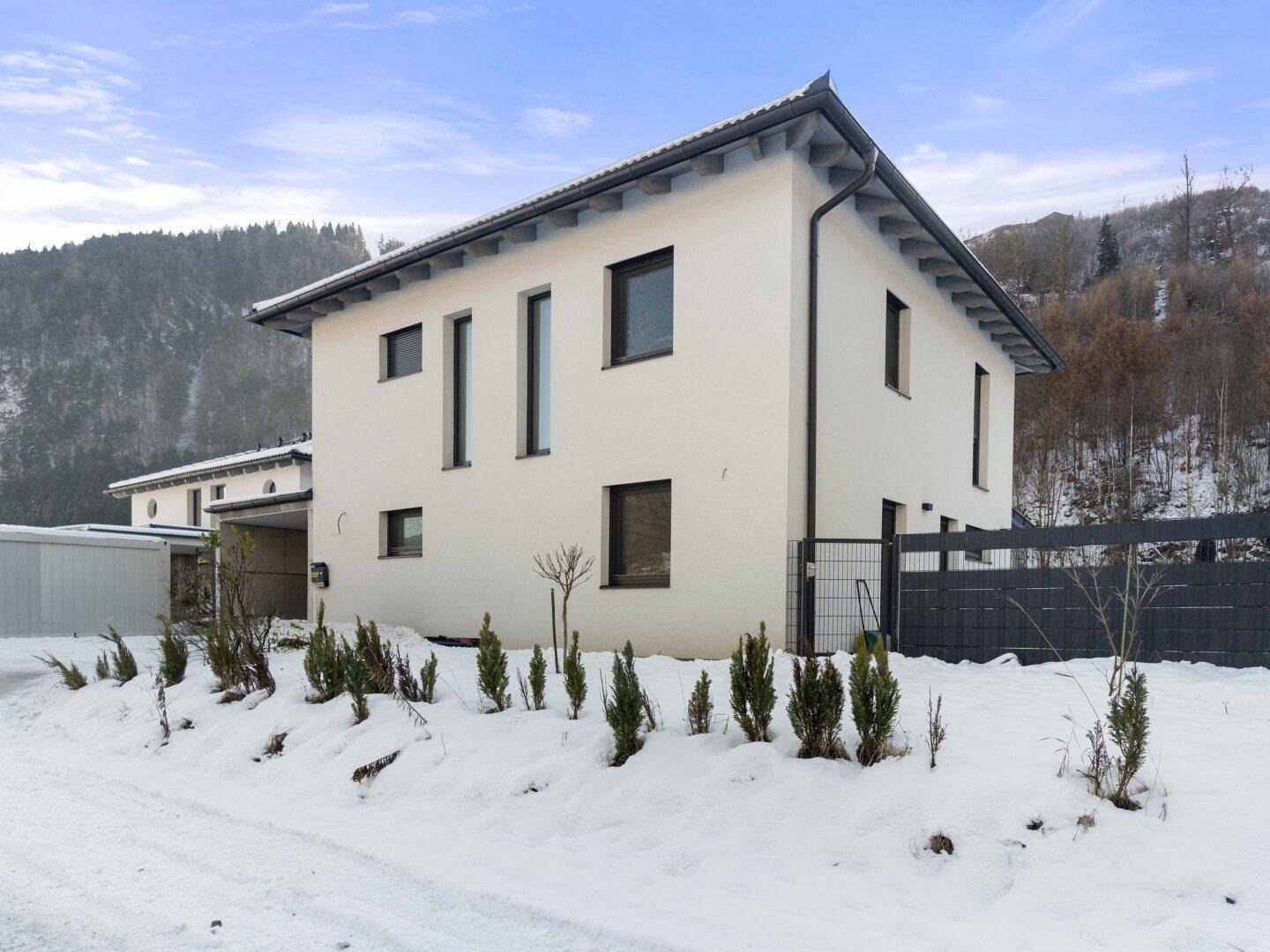 Modernes Einfamilienhaus in winterlicher Berglandschaft mit weißer Fassade.