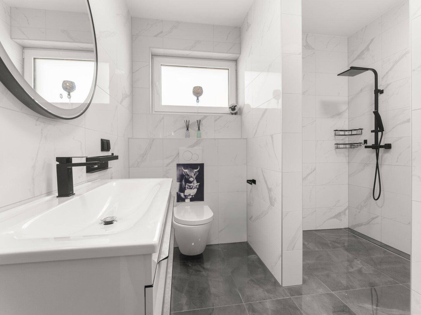 Modernes Badezimmer mit weißen Marmorfliesen, ebenerdiger Dusche und Fenster.