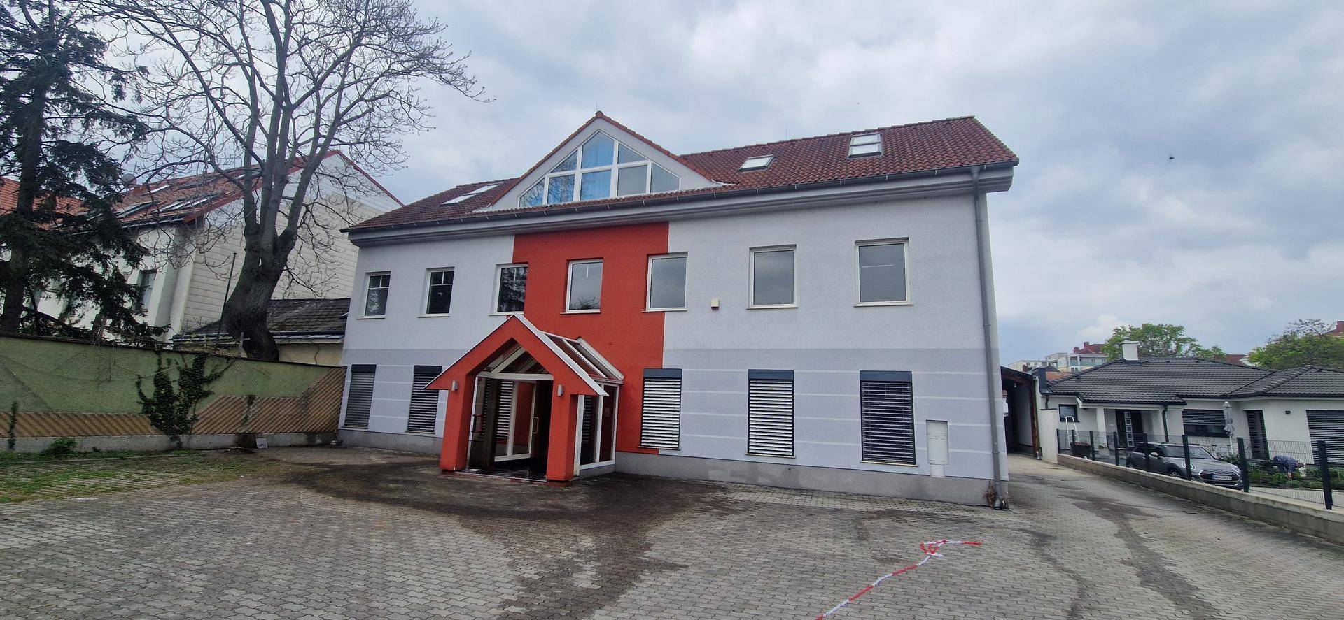 Außenansicht des Gebäudes mit gepflastertem Vorplatz und Zufahrt.